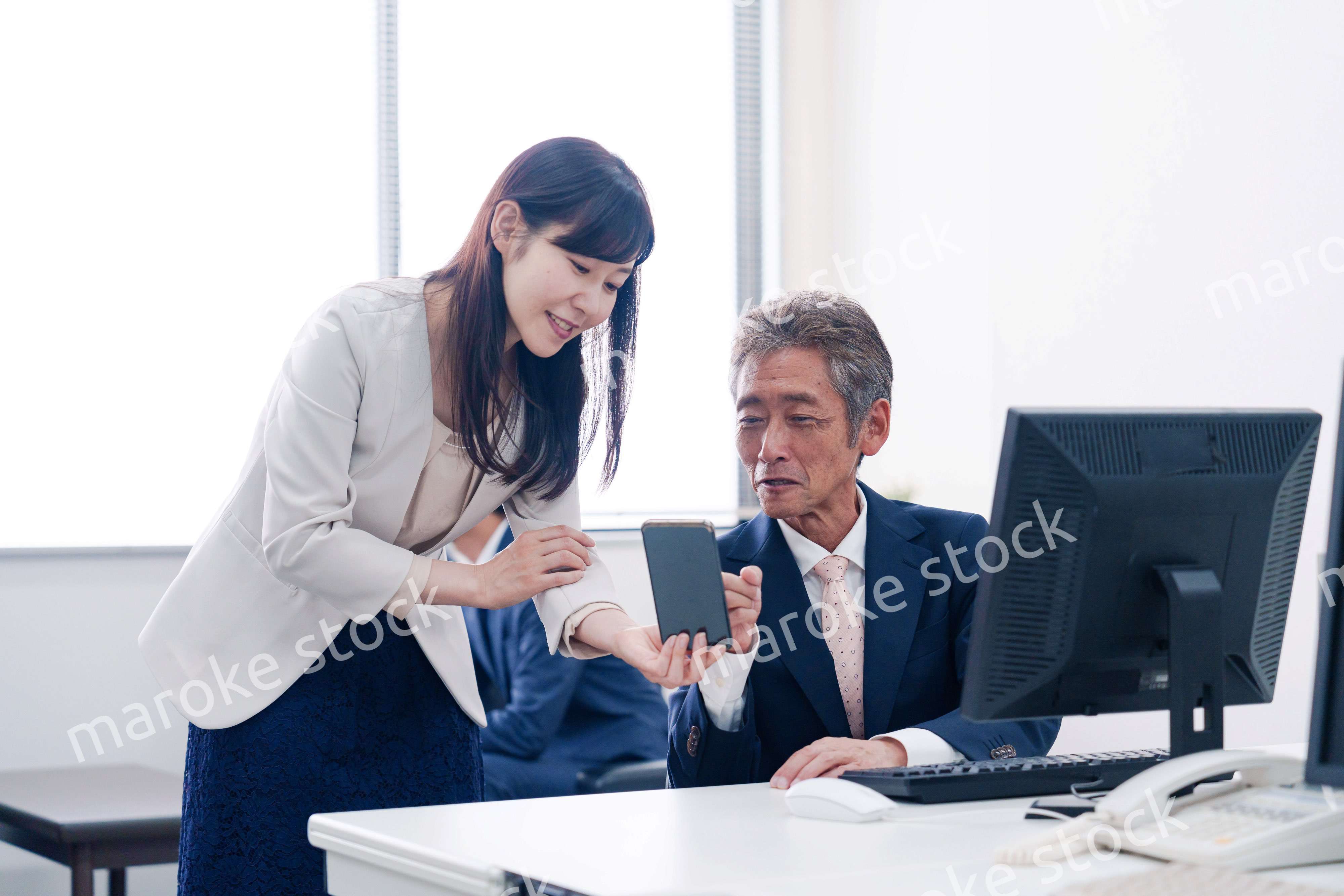 上司にスマホを見せる女性社員