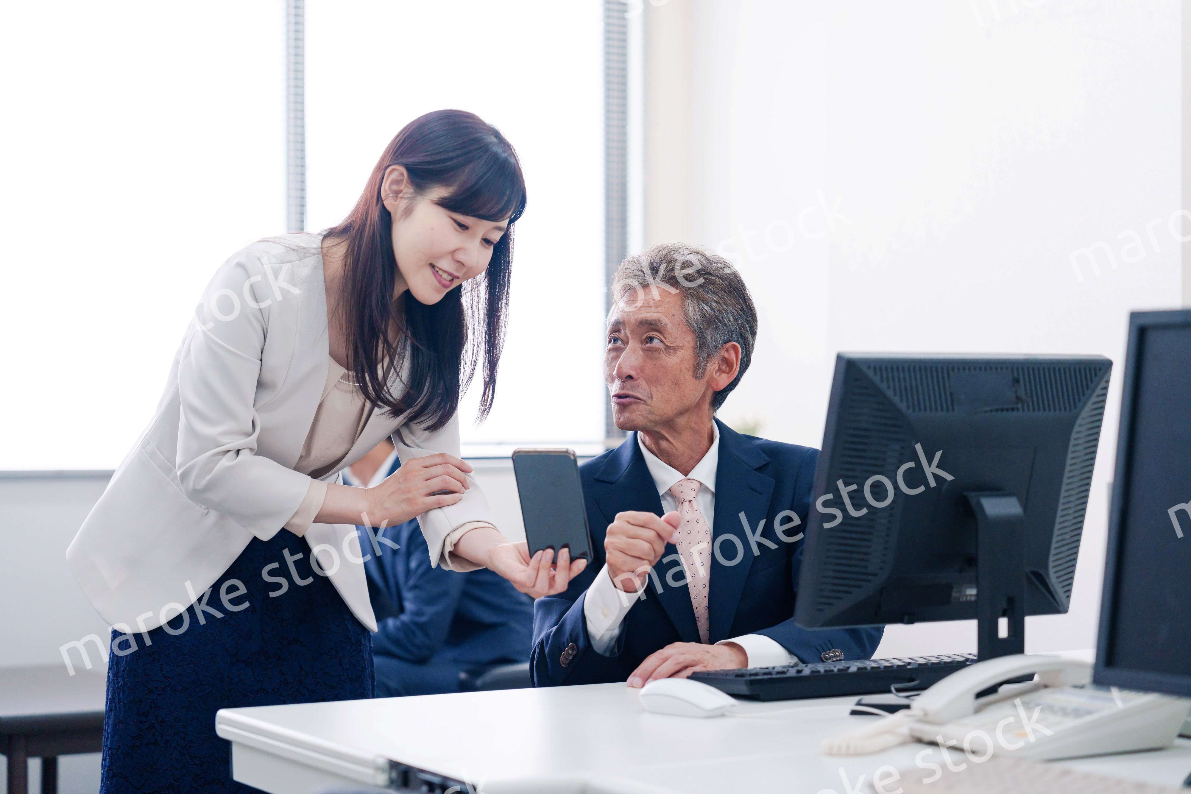 上司にスマホを見せる女性社員