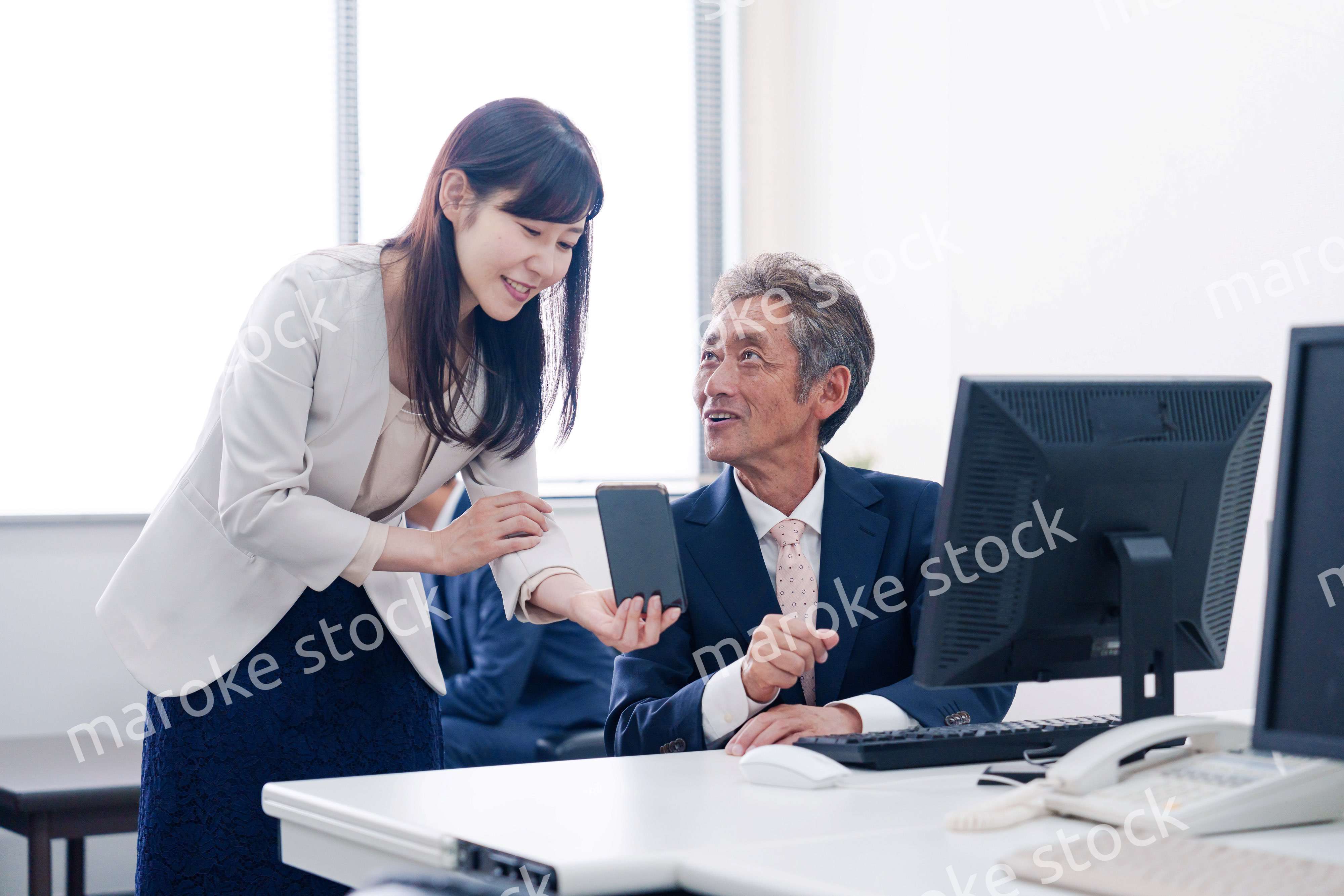 上司にスマホを見せる女性社員