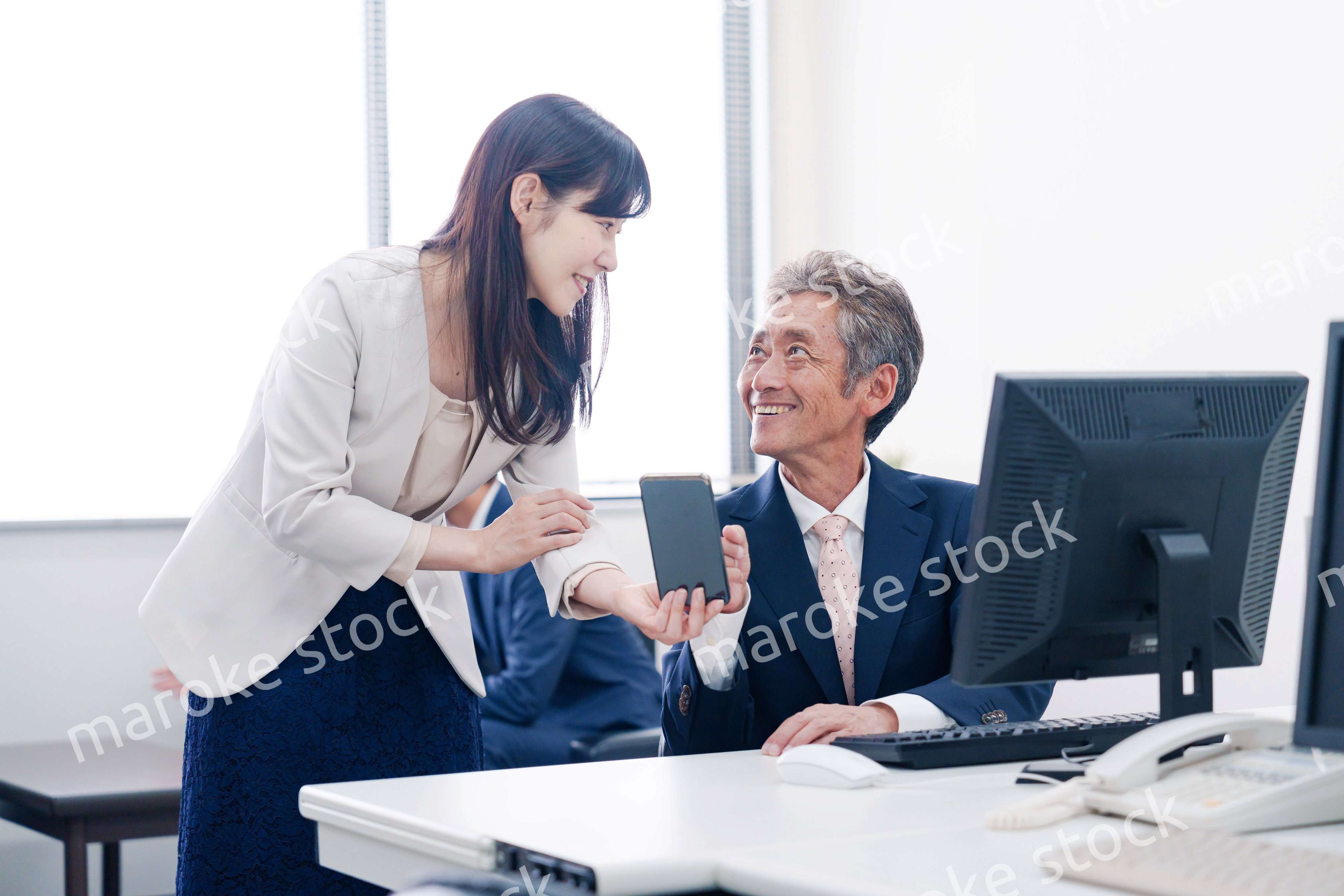 上司にスマホを見せる女性社員