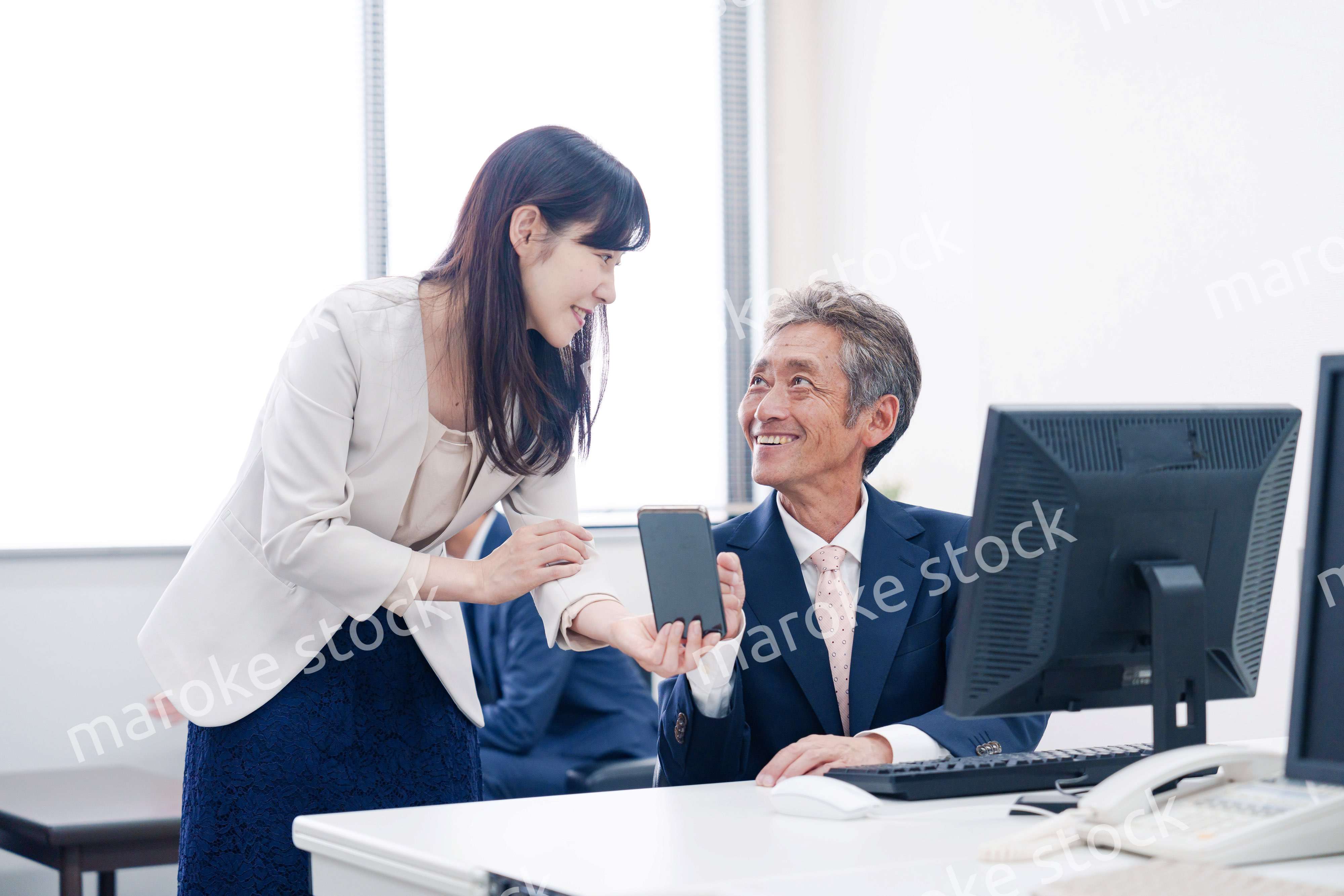 上司にスマホを見せる女性社員