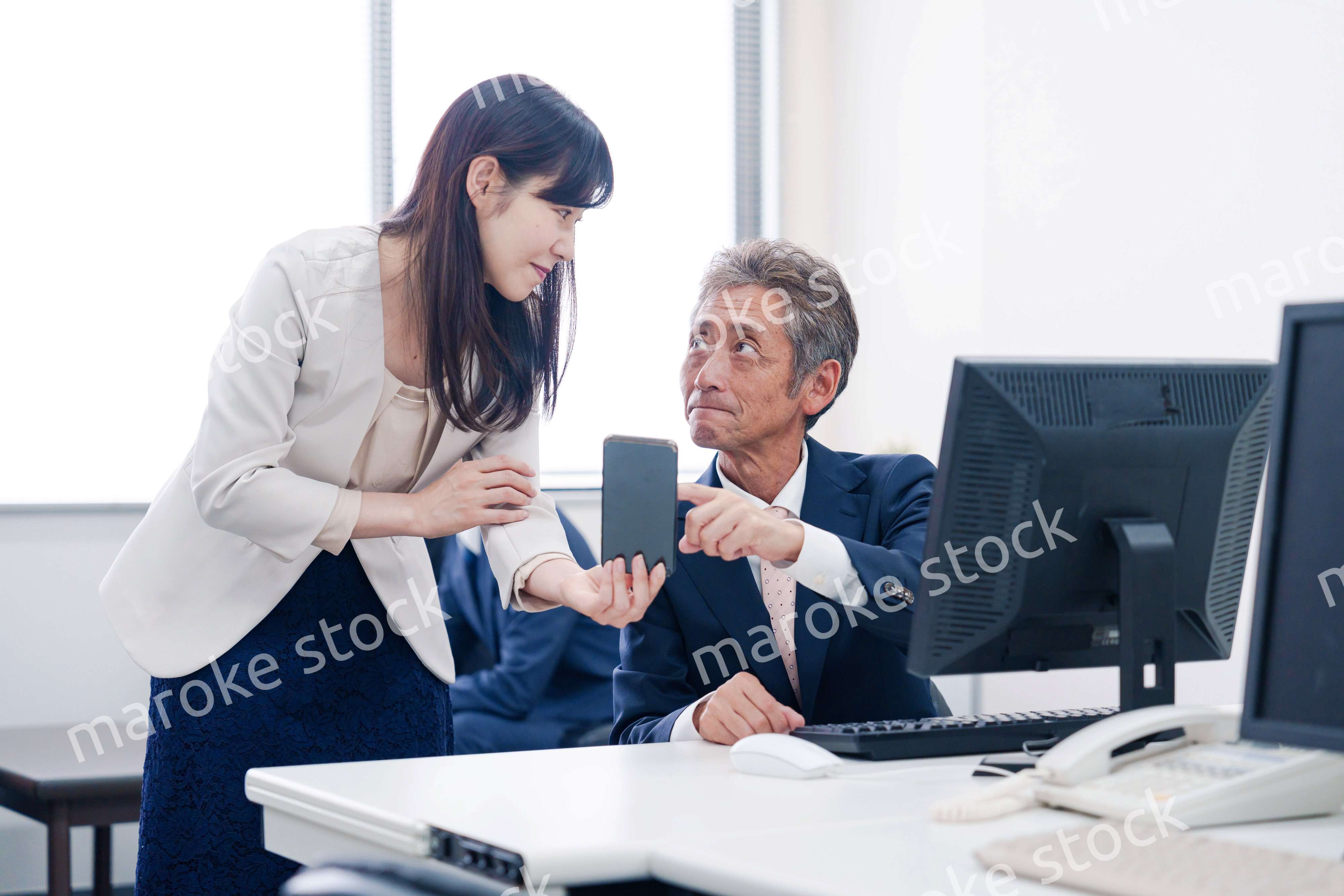 上司にスマホを見せる女性社員
