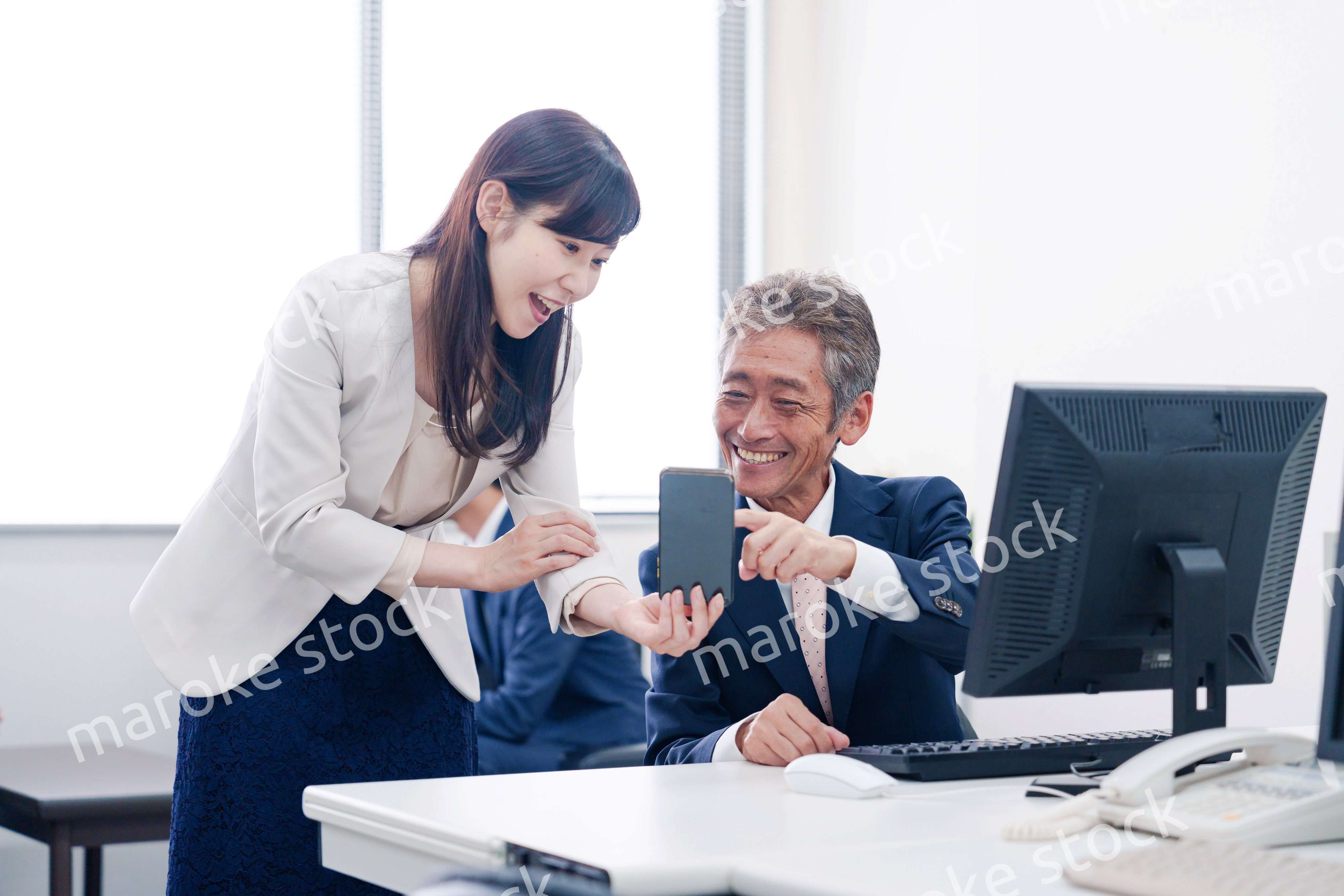 上司にスマホを見せる女性社員