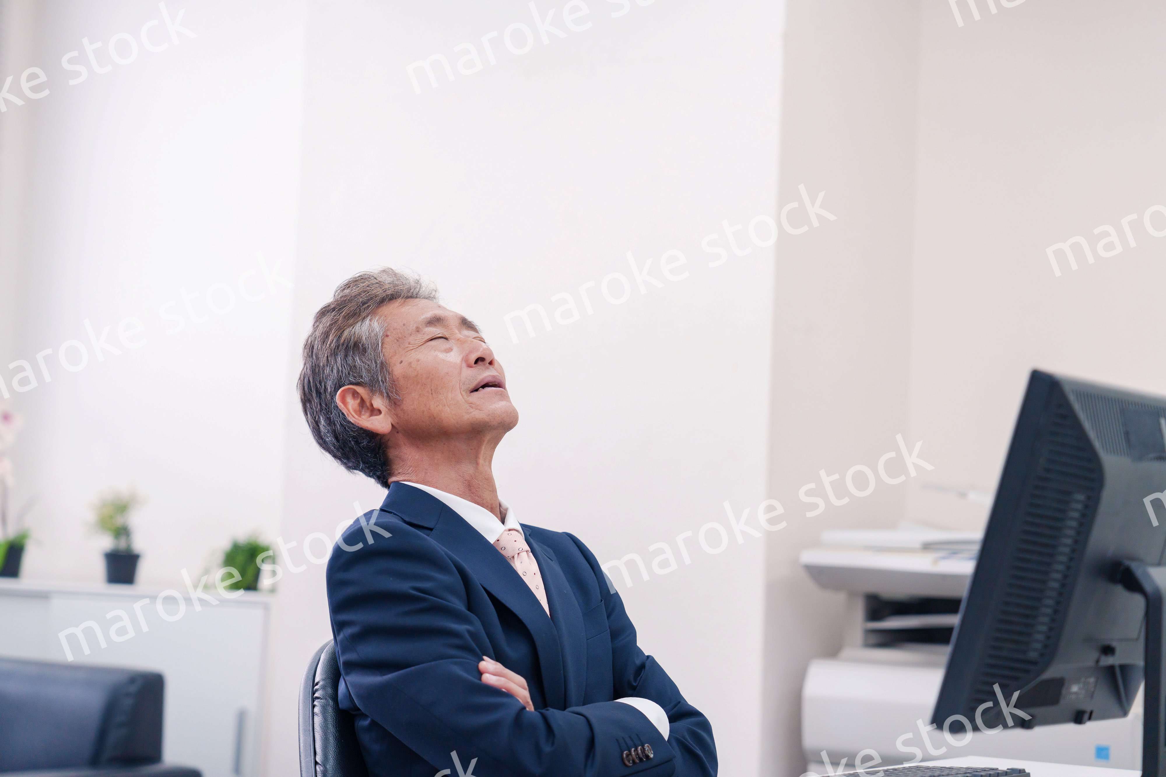 オフィスで腕を組んで悩む中年の上司