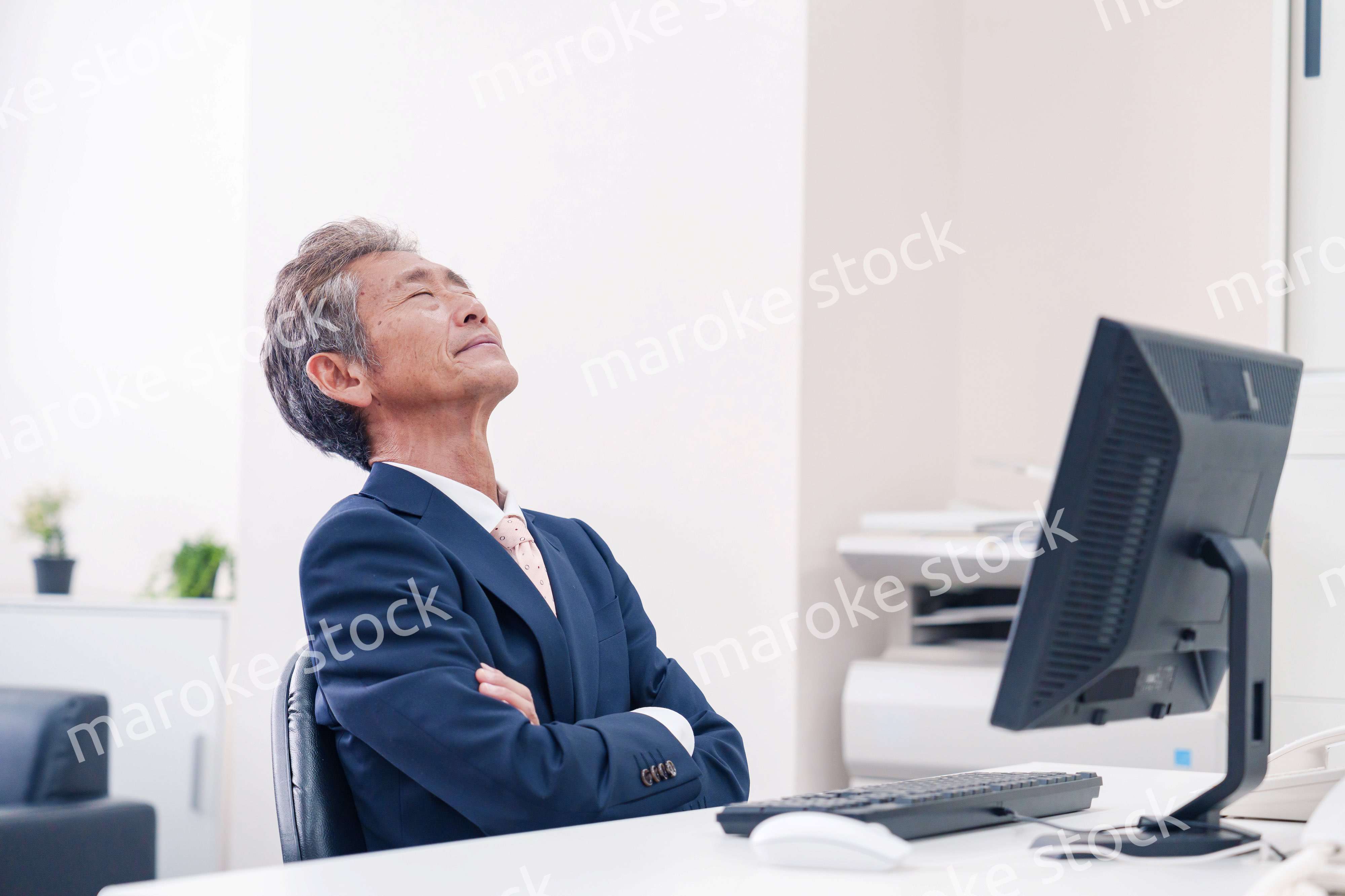 オフィスで腕を組んで悩む中年の上司