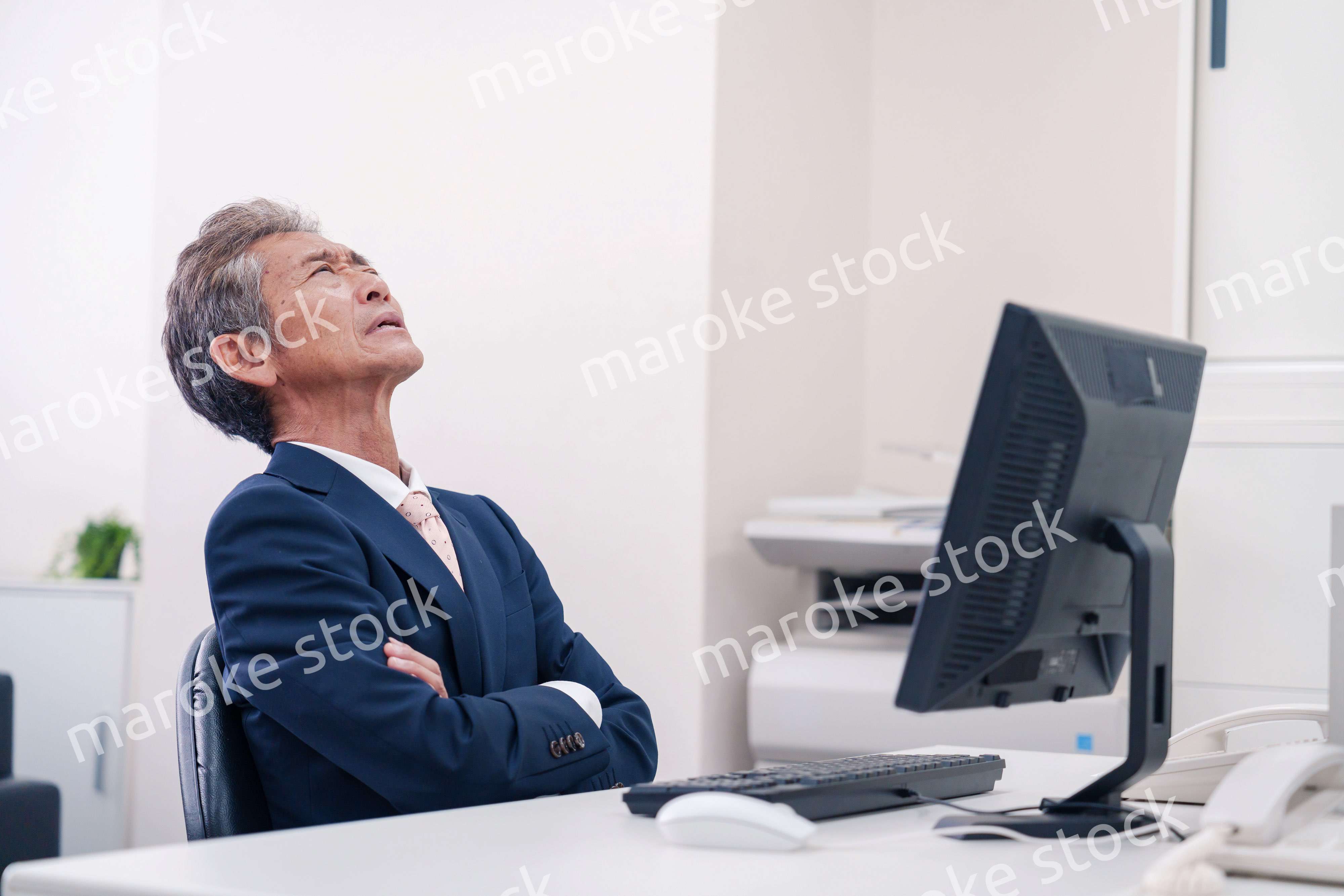 オフィスで腕を組んで悩む中年の上司