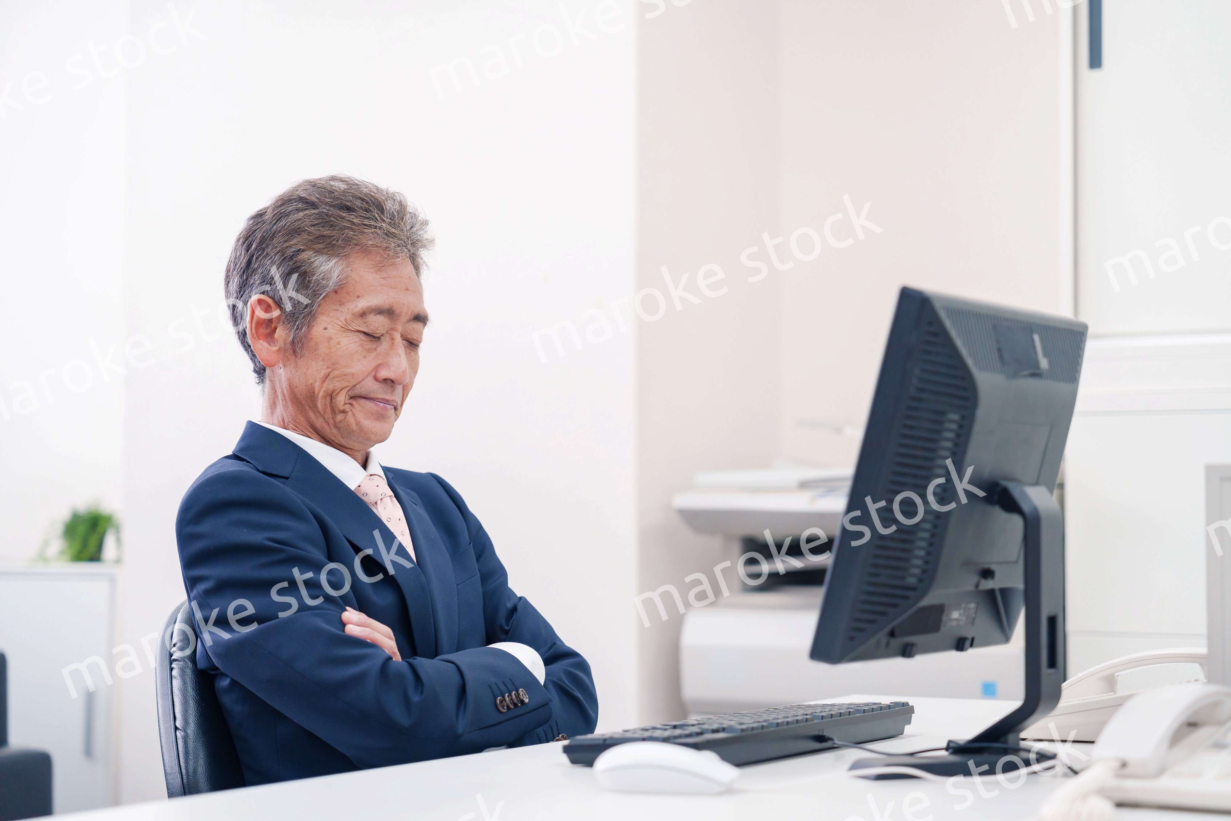 オフィスで腕を組んで悩む中年の上司