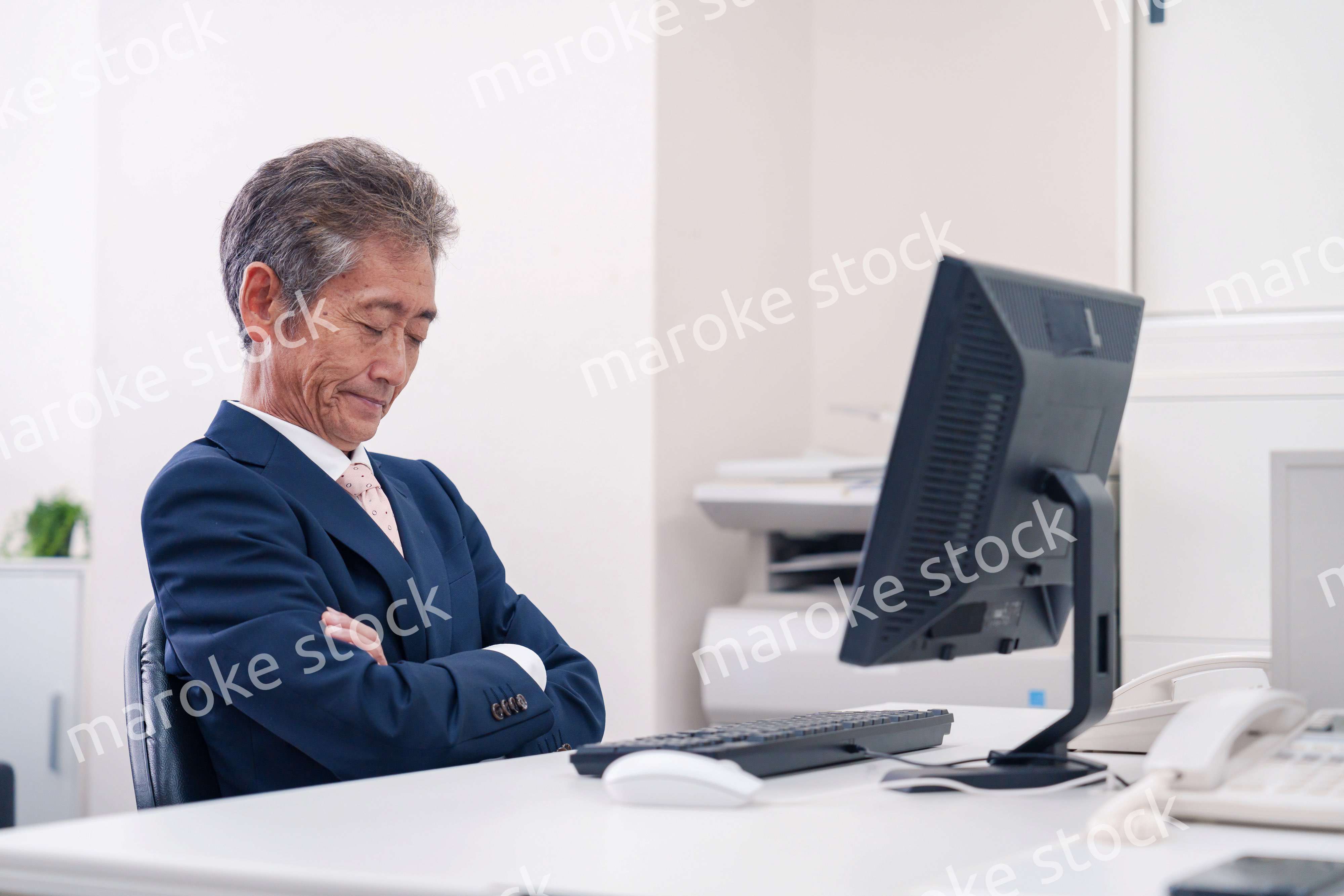 オフィスで腕を組んで悩む中年の上司