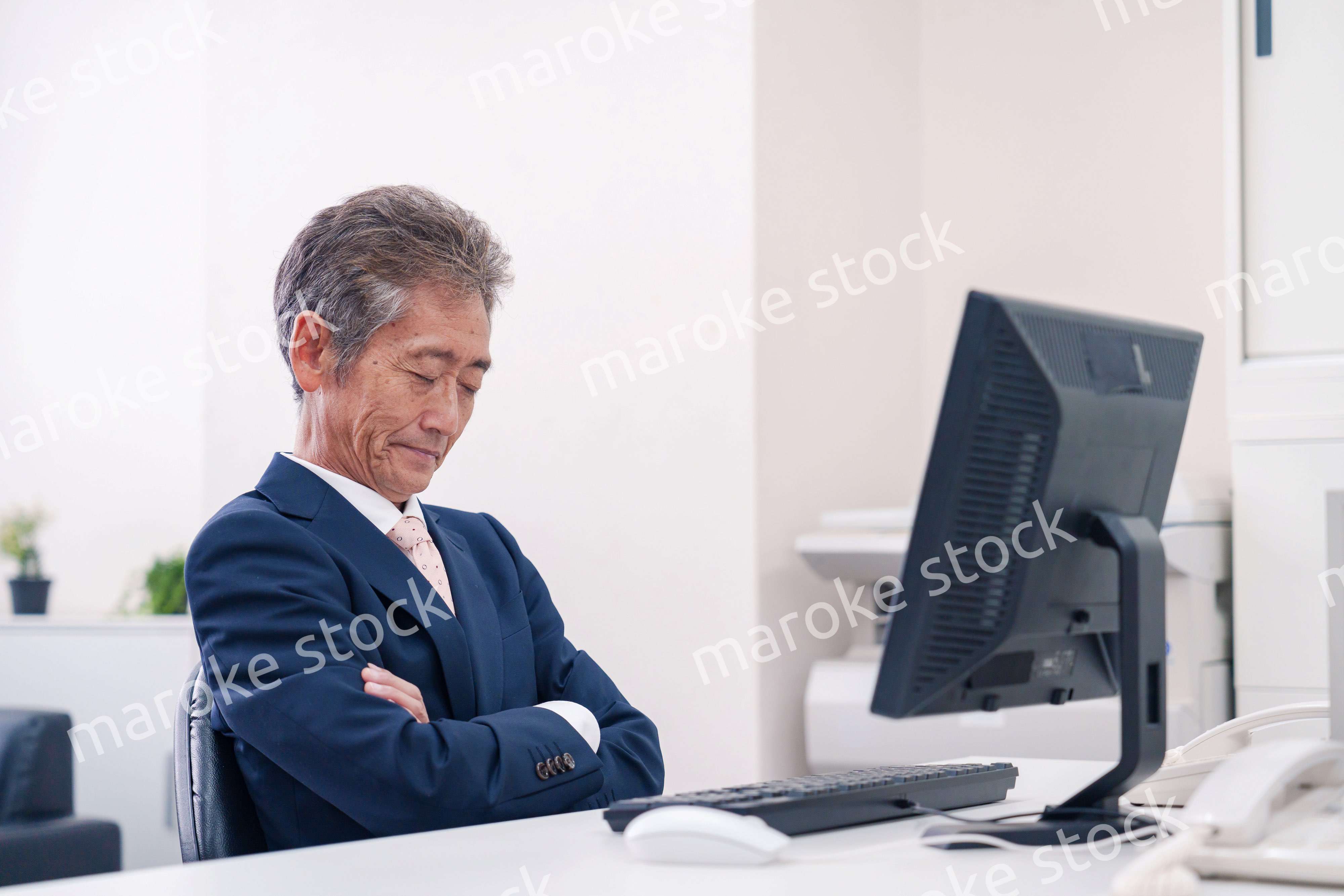 オフィスで腕を組んで悩む中年の上司