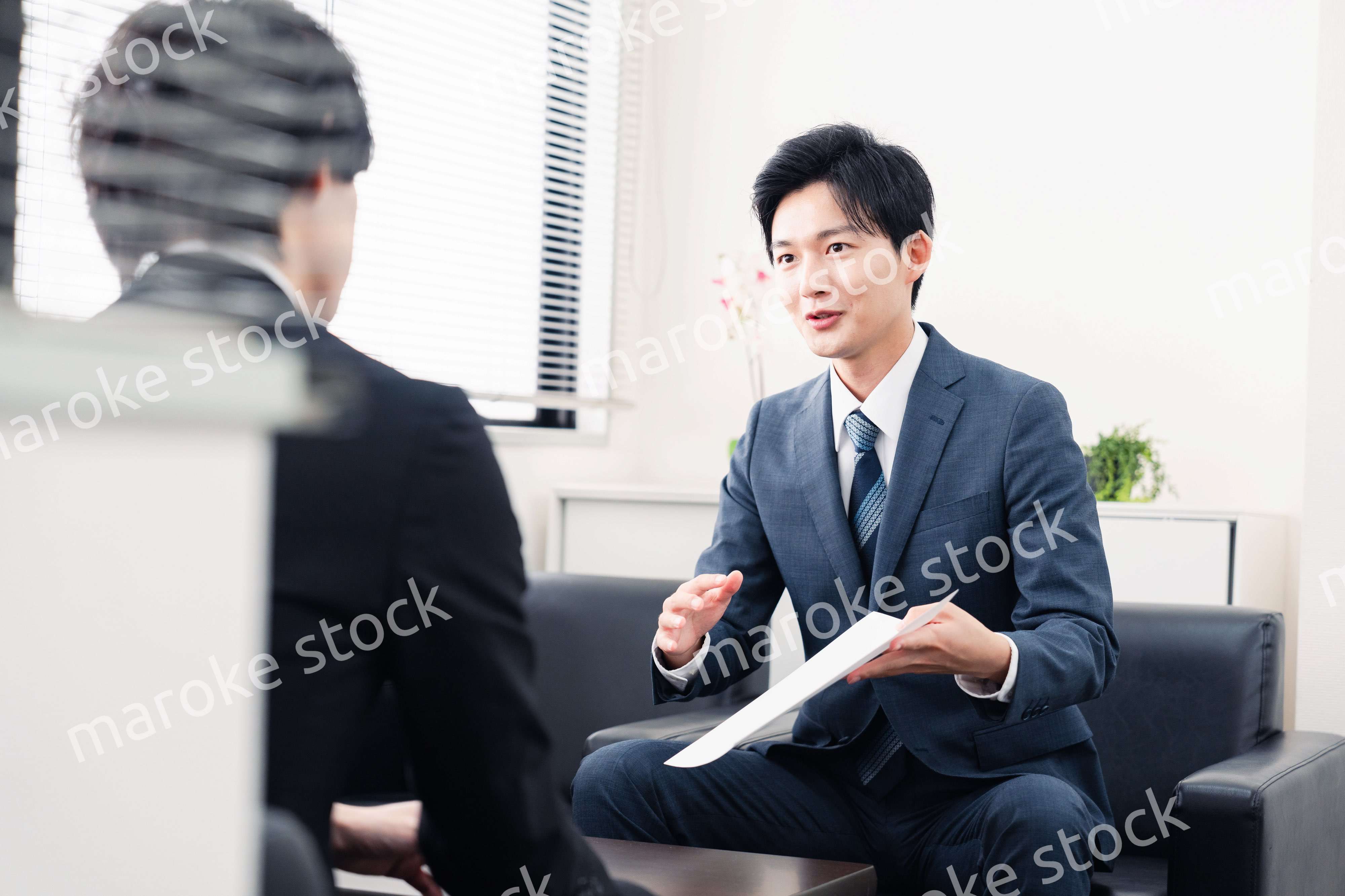 商談で書類を提示するビジネスマン