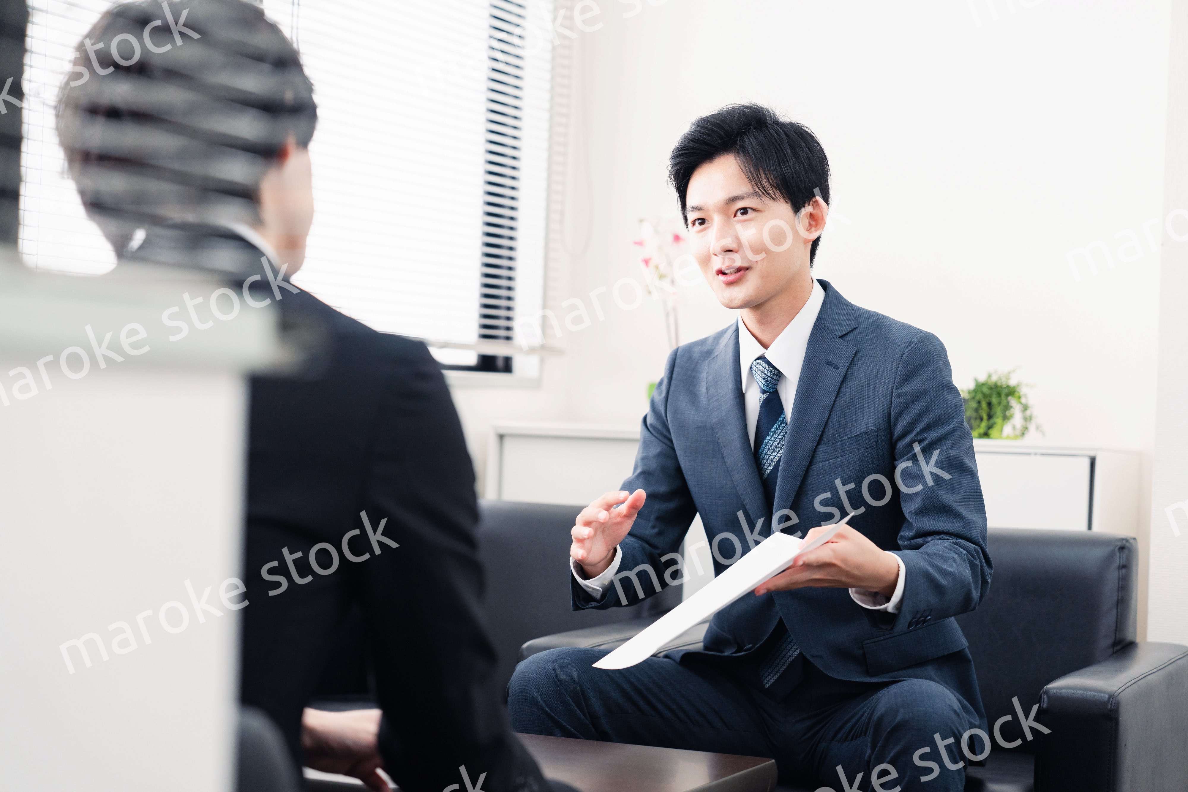 商談で書類を提示するビジネスマン