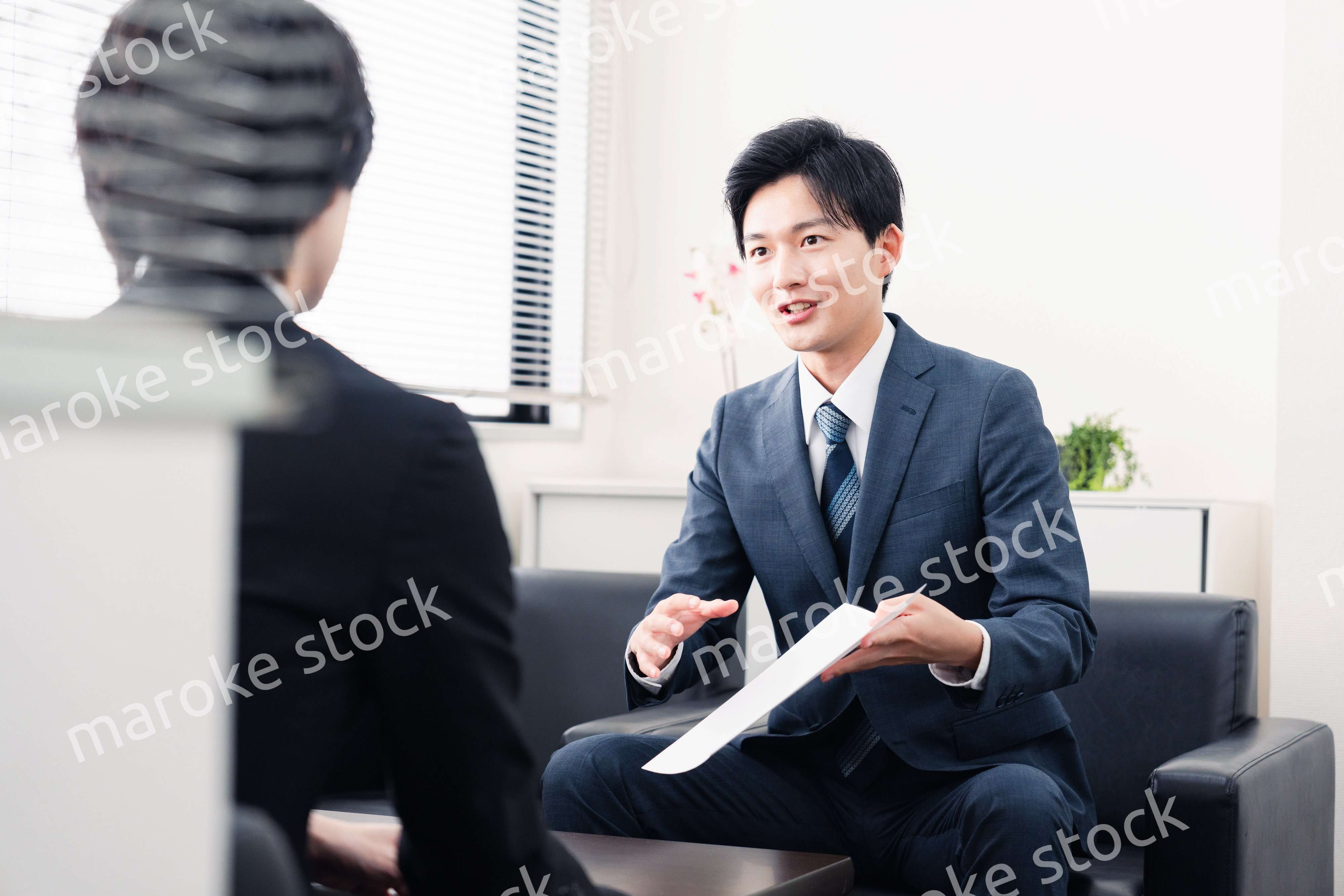 商談で書類を提示するビジネスマン