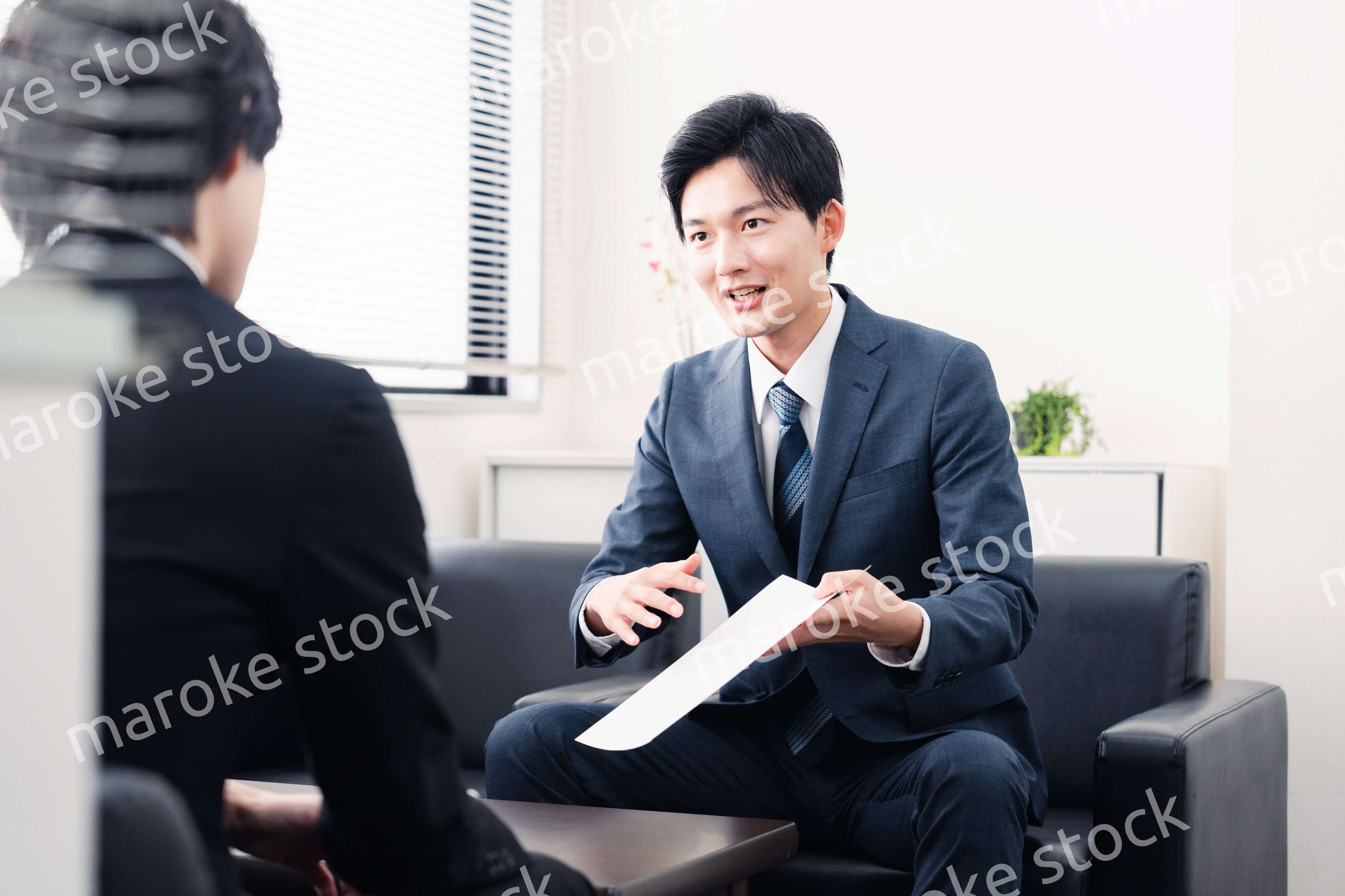 商談で書類を提示するビジネスマン