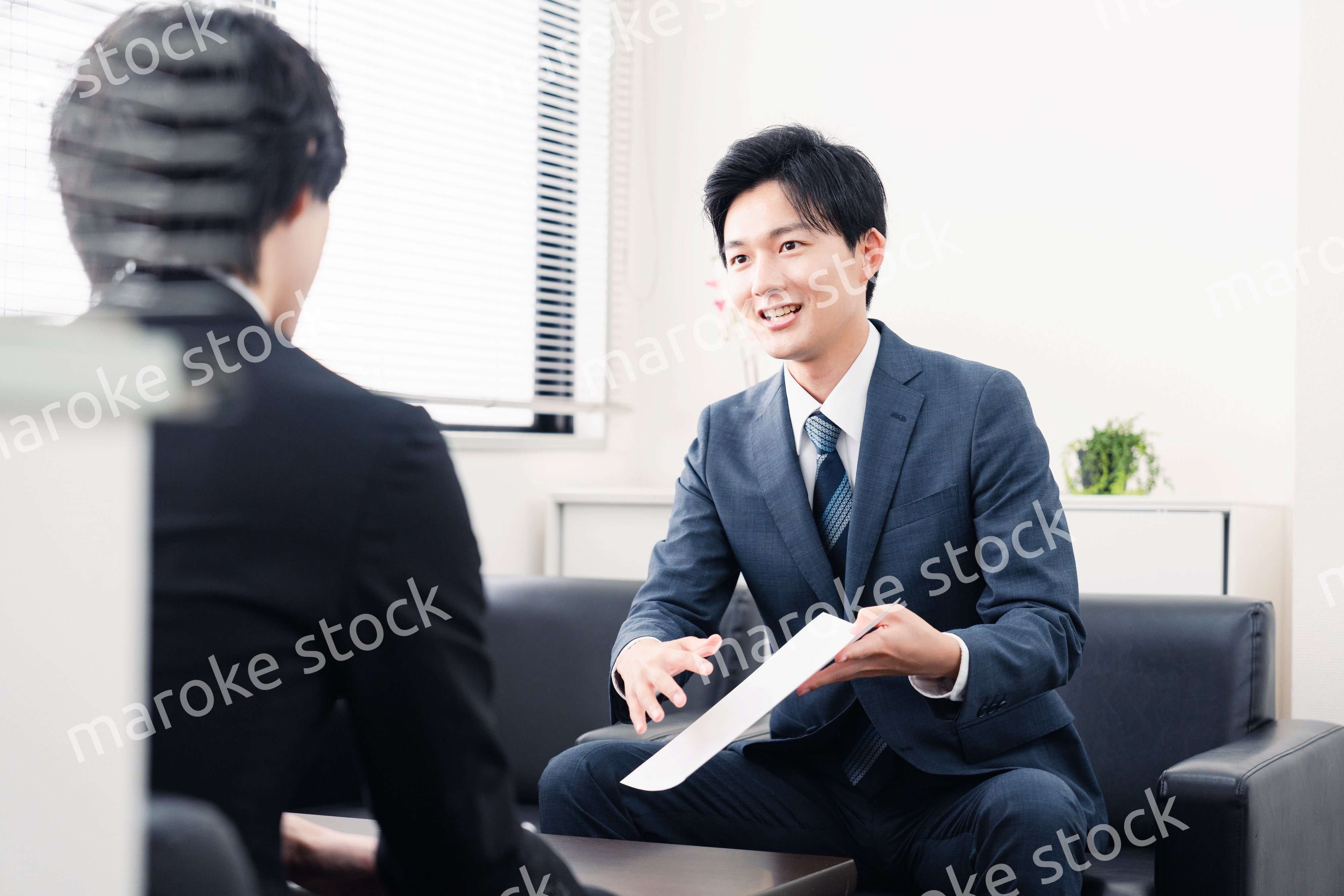 商談で書類を提示するビジネスマン