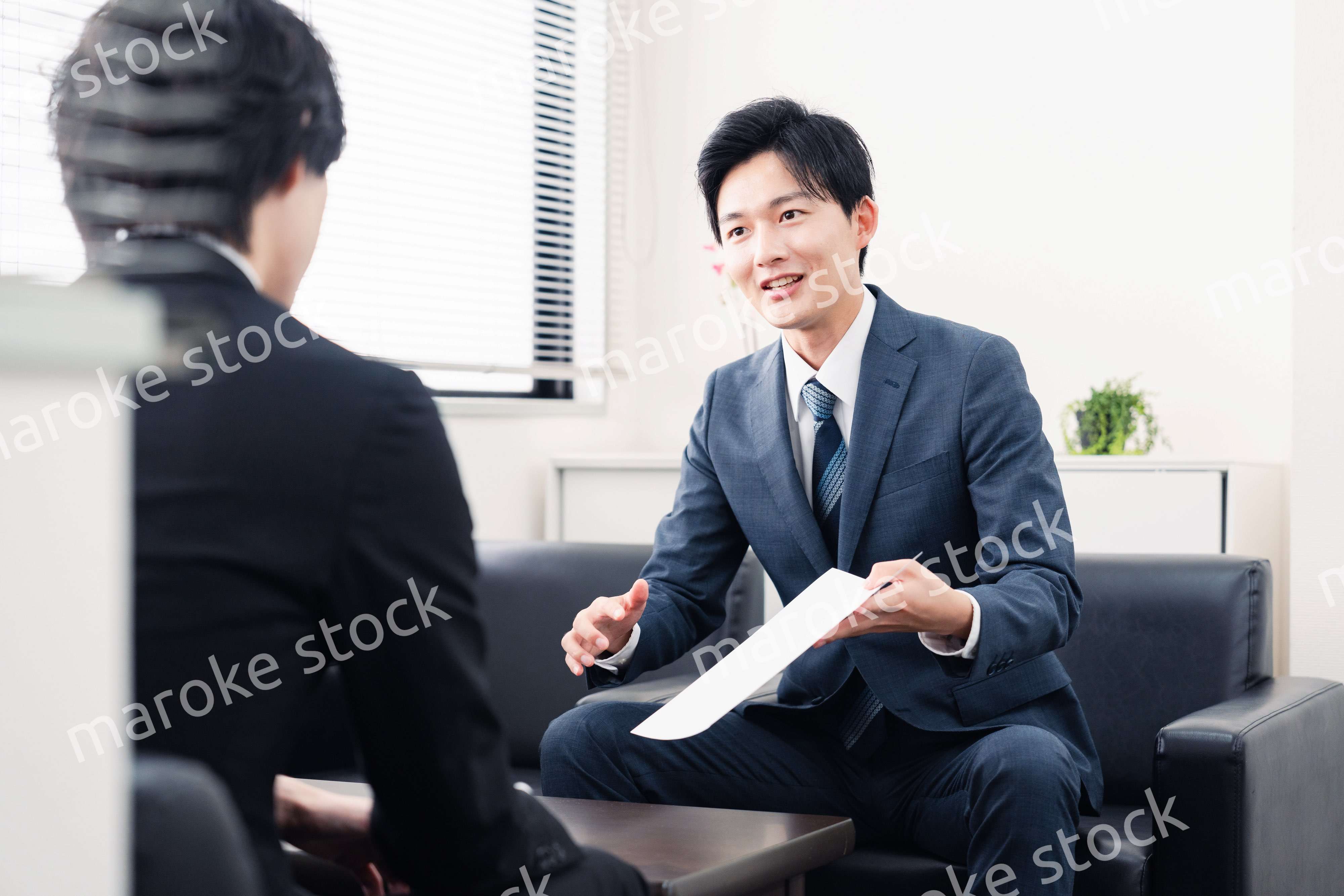 商談で書類を提示するビジネスマン