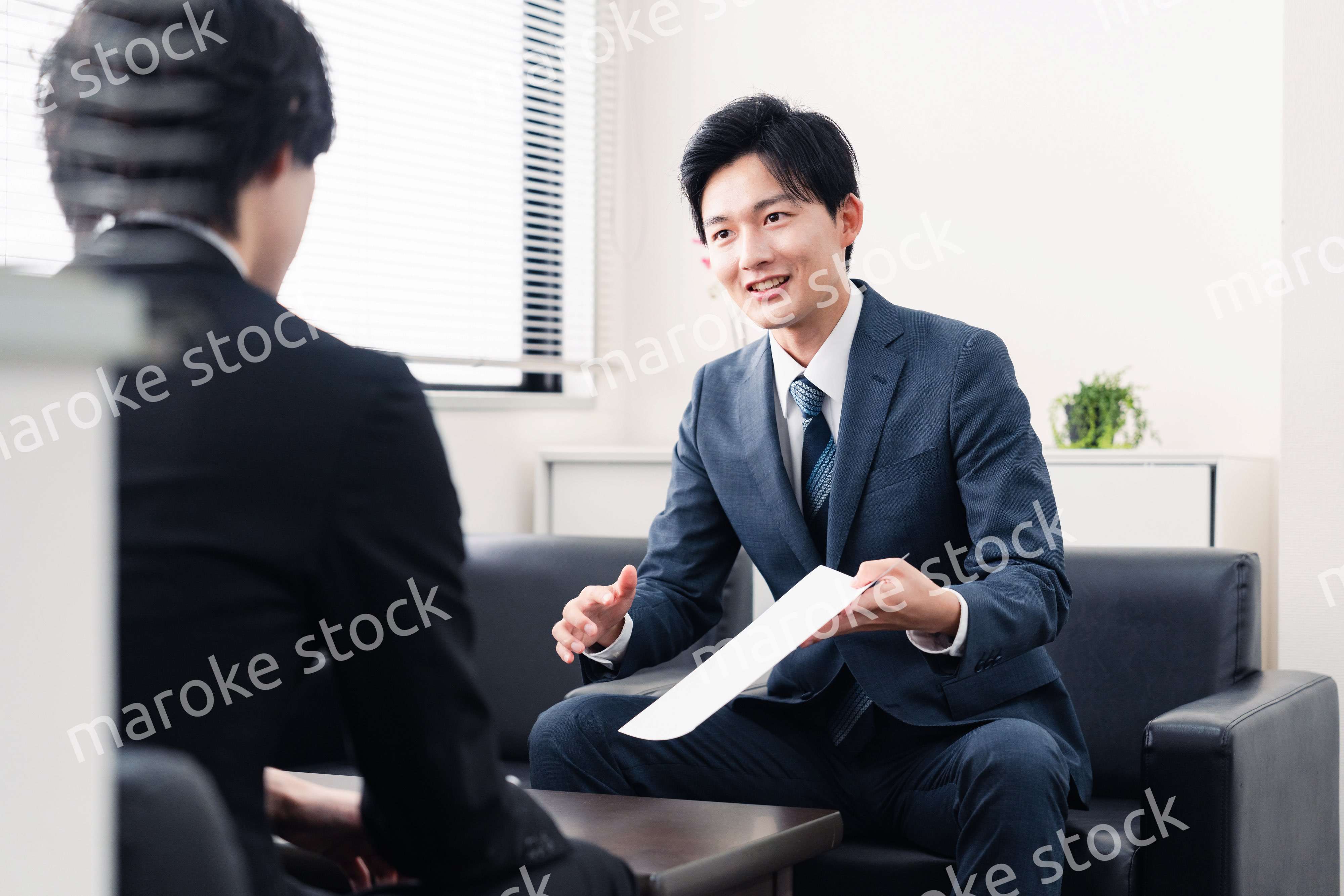 商談で書類を提示するビジネスマン