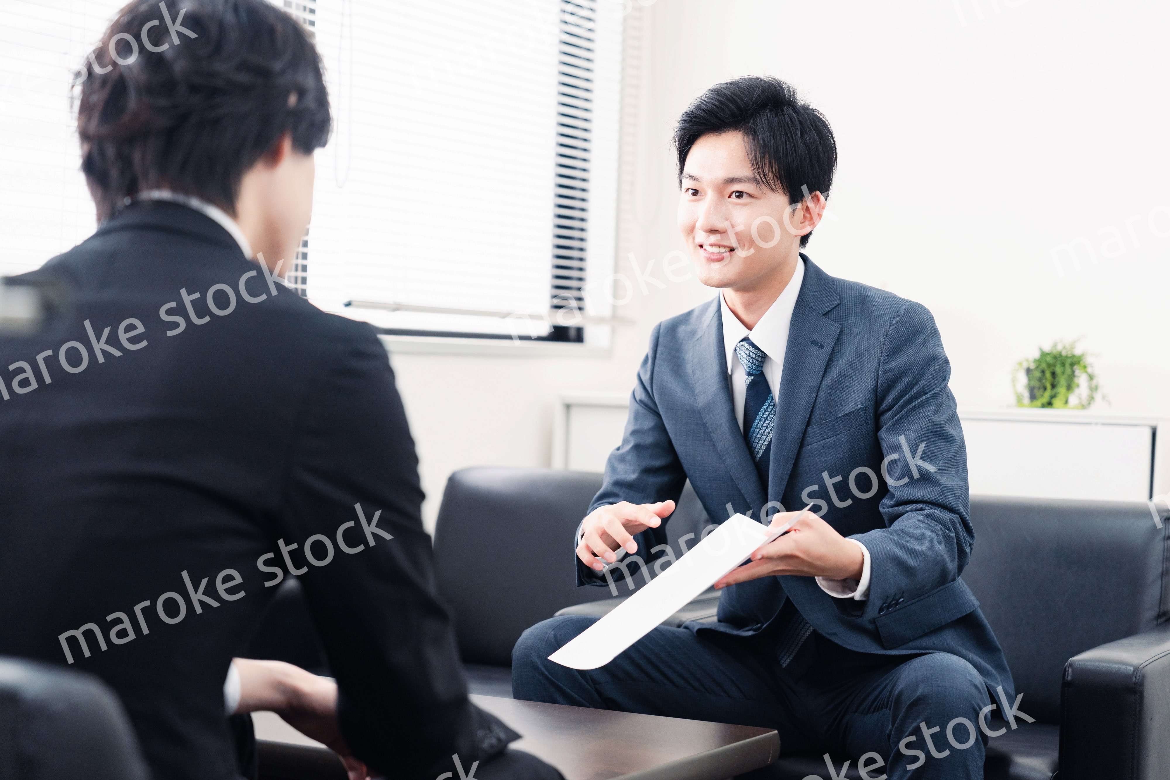 商談で書類を提示するビジネスマン
