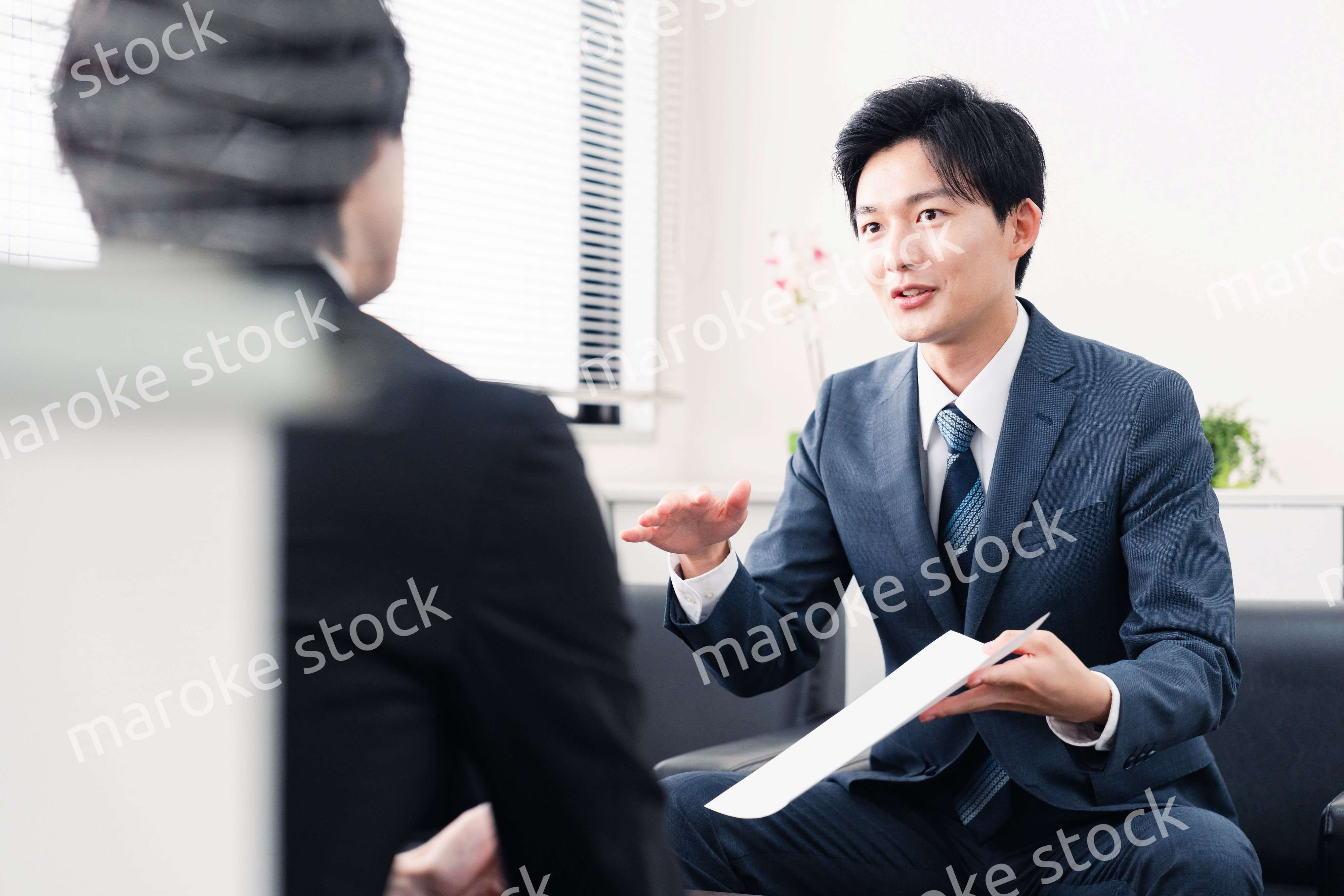 商談で書類を提示するビジネスマン