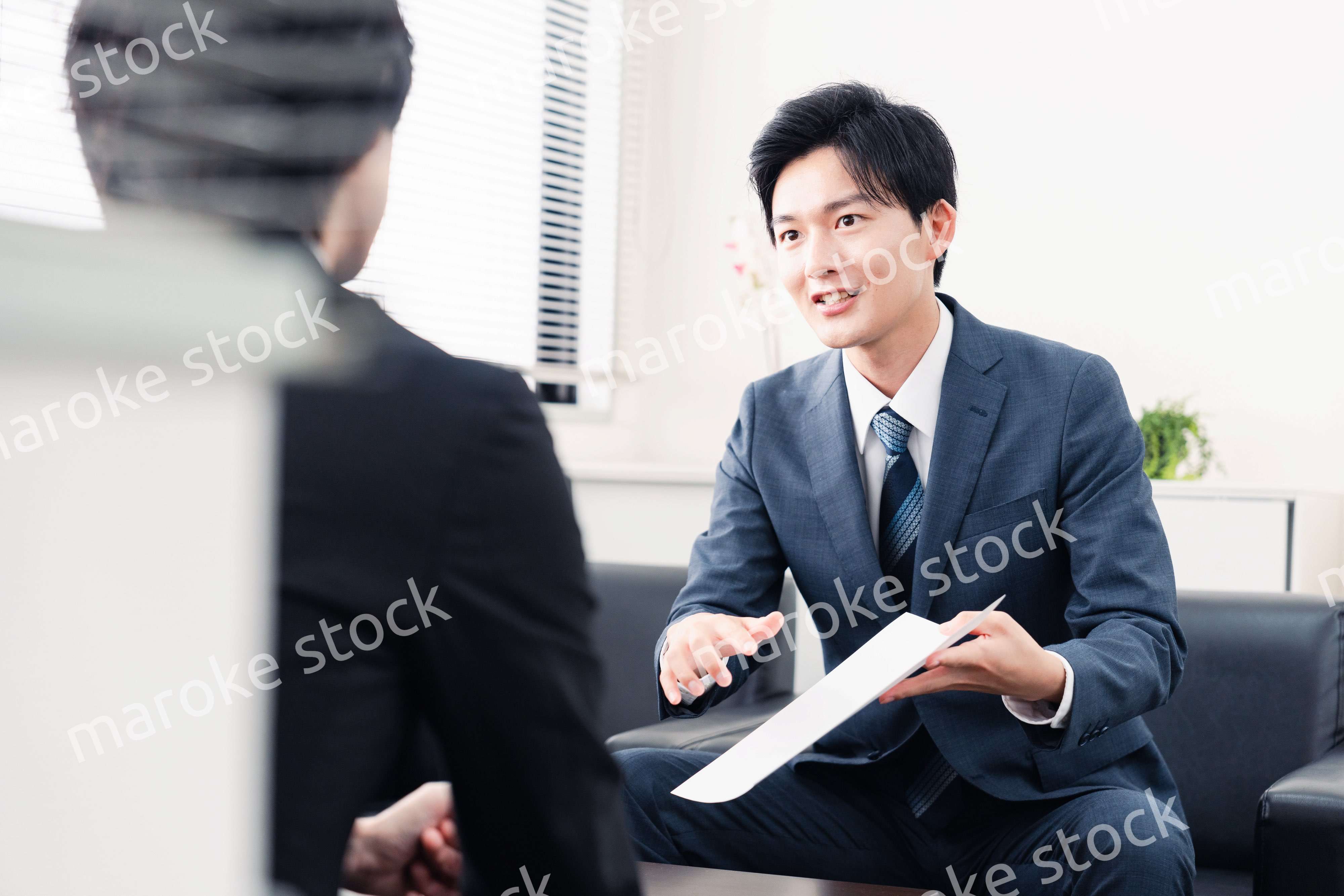 商談で書類を提示するビジネスマン