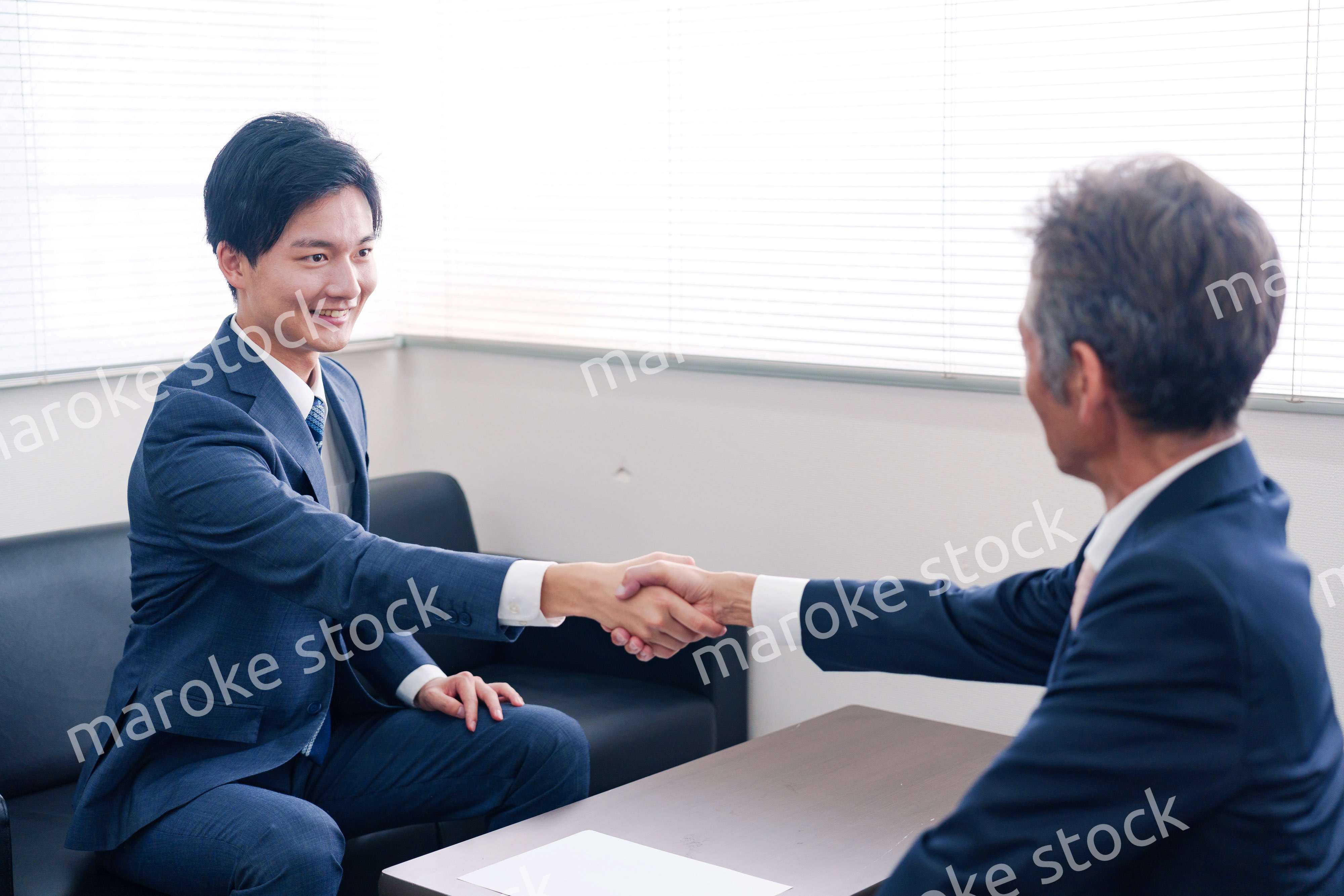 得意先と握手をするビジネスマン