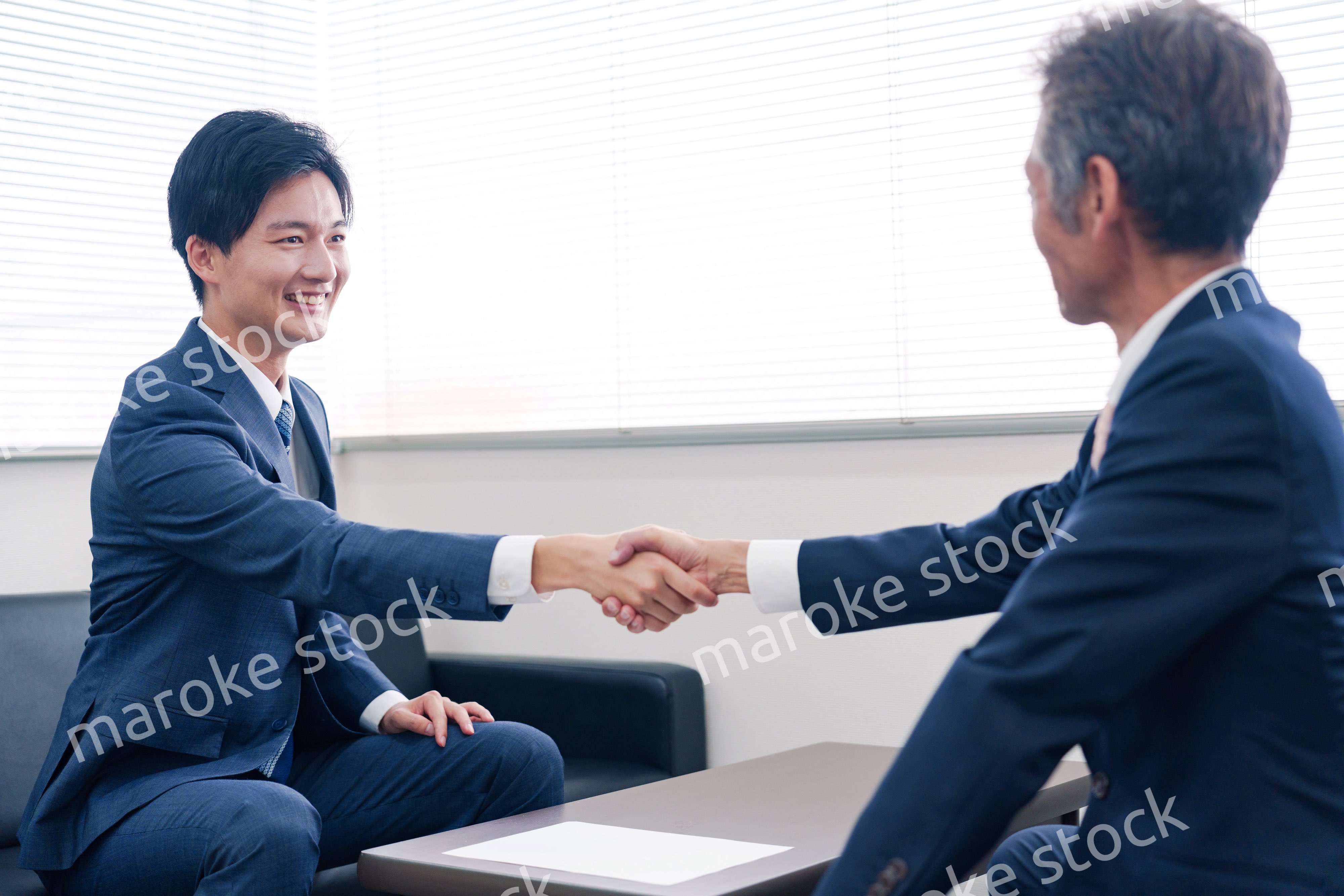 得意先と握手をするビジネスマン