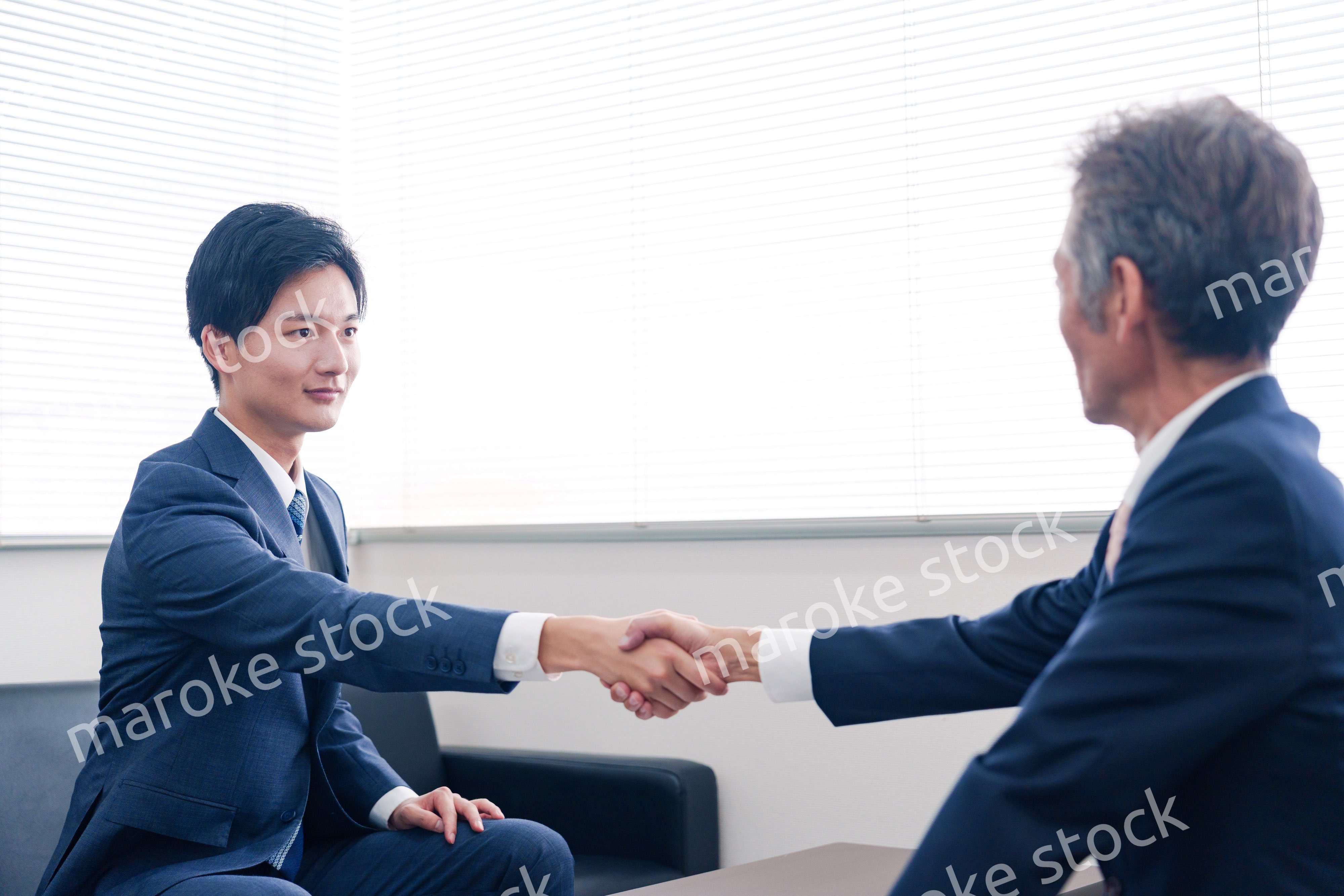 得意先と握手をするビジネスマン