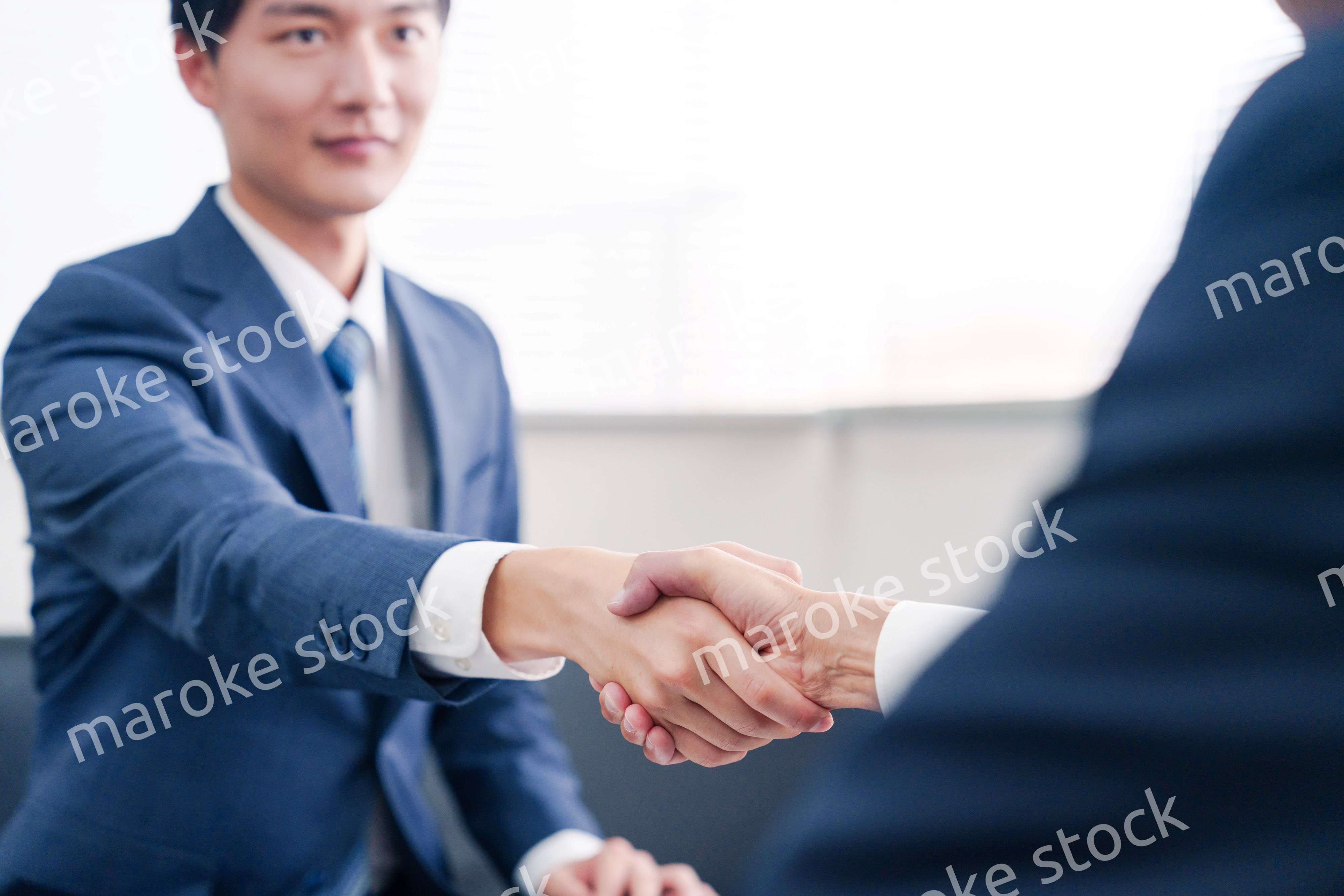 得意先と握手をするビジネスマン