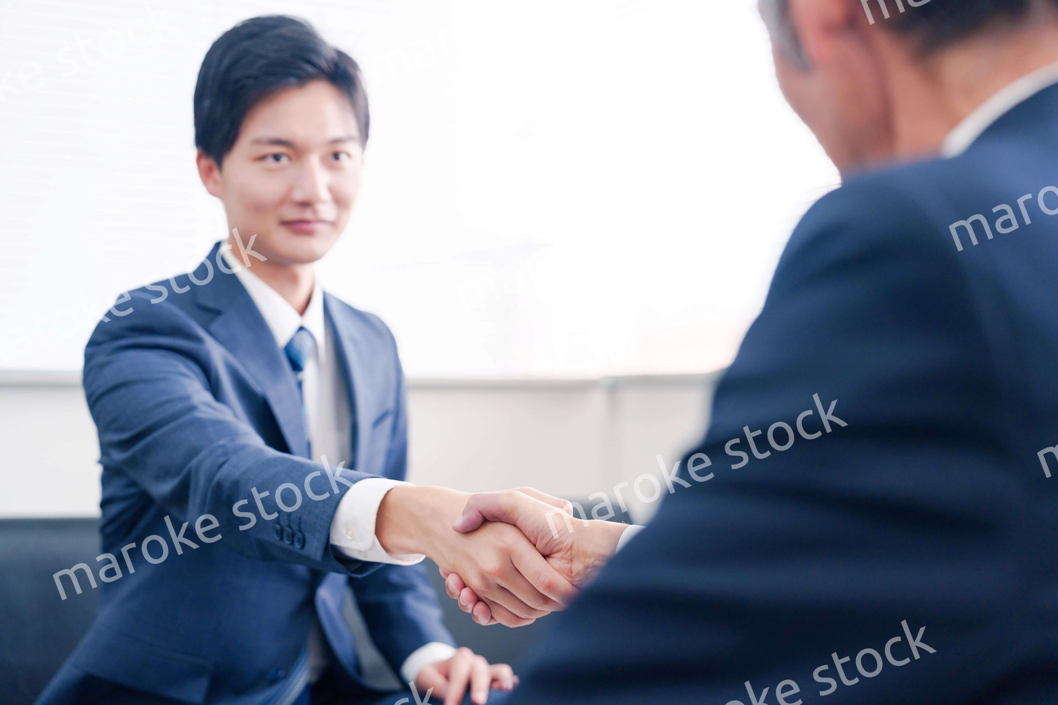 得意先と握手をするビジネスマン