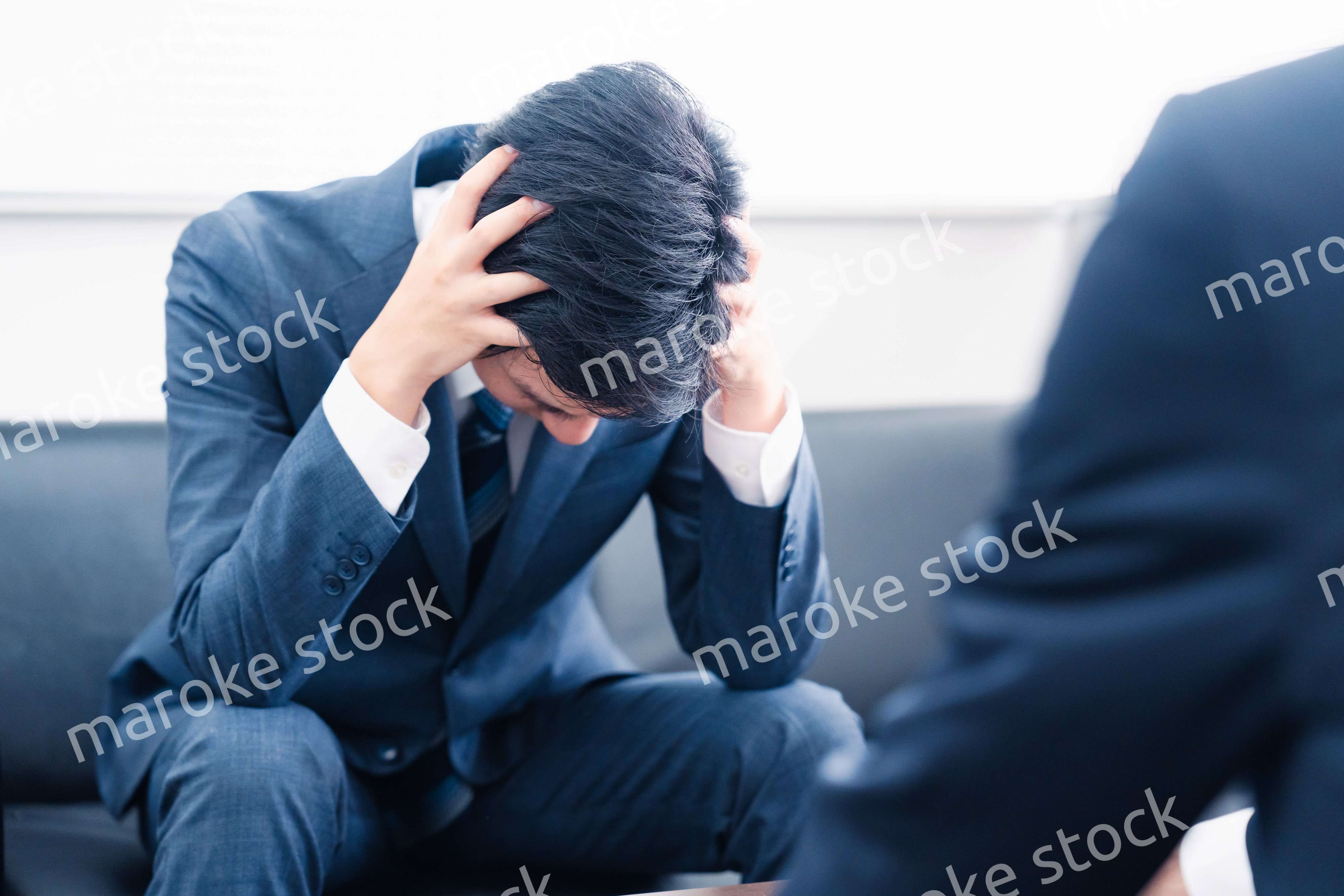 上司に呼び出されて頭を抱えるビジネスマン