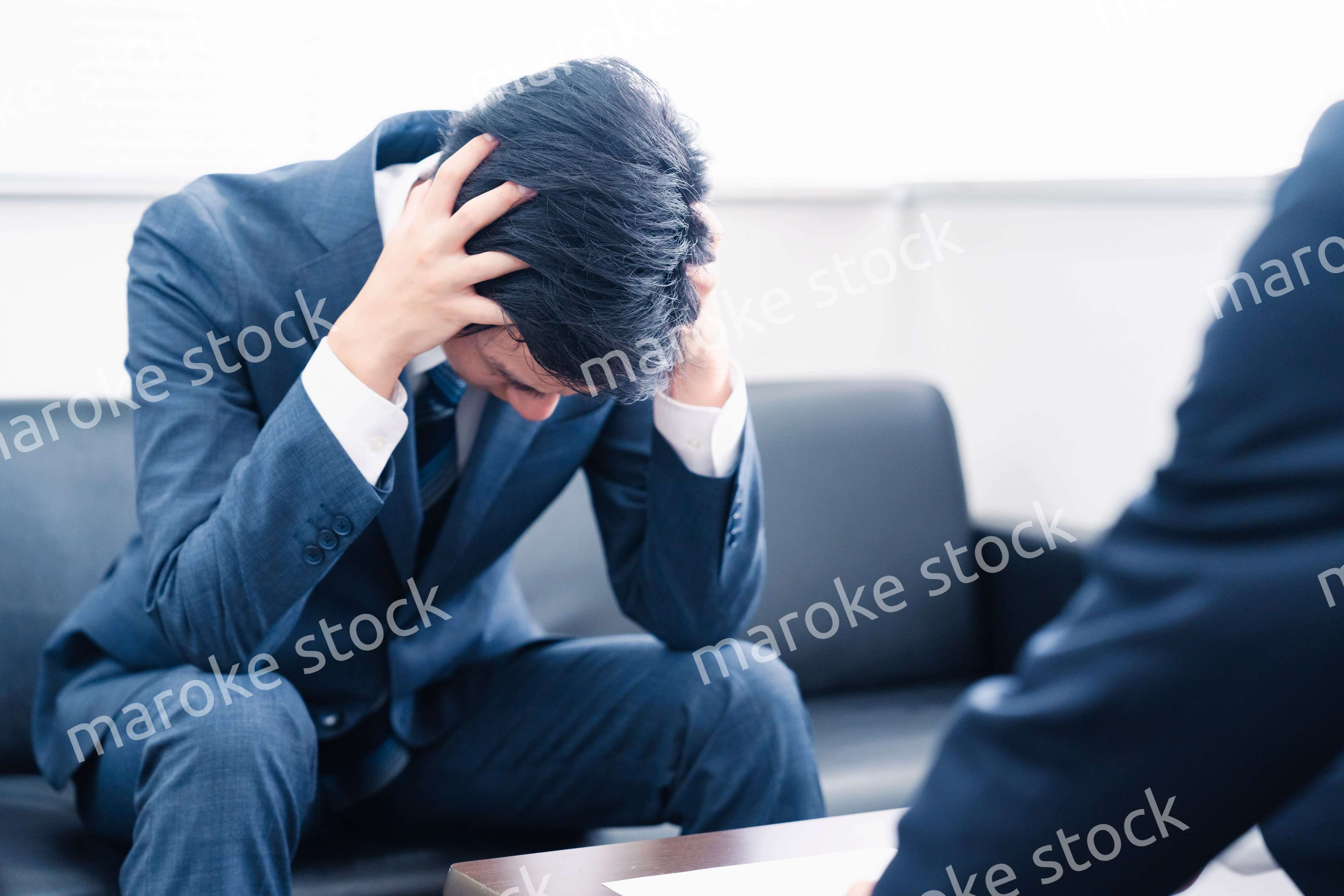 上司に呼び出されて頭を抱えるビジネスマン