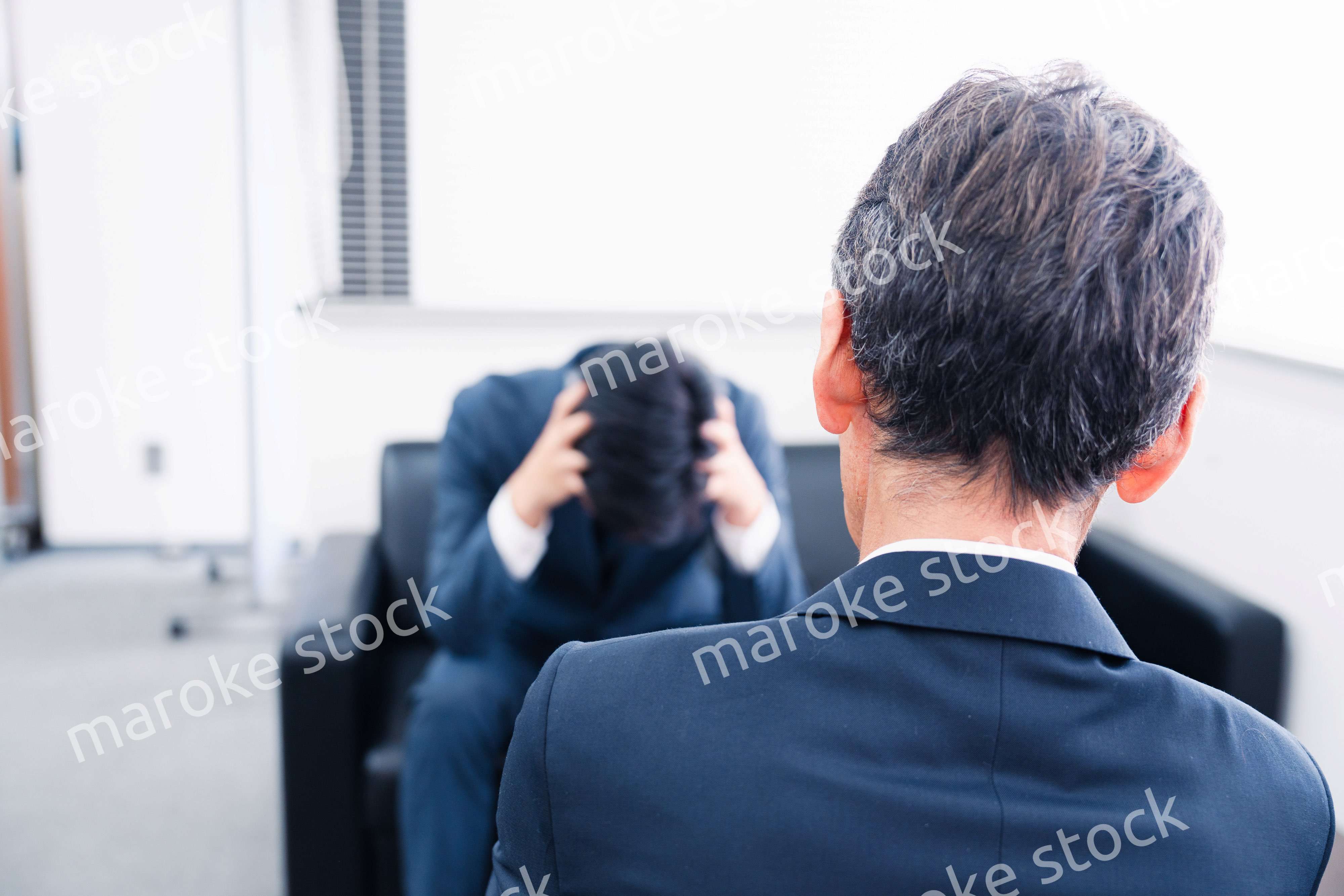 上司に呼び出されて頭を抱えるビジネスマン