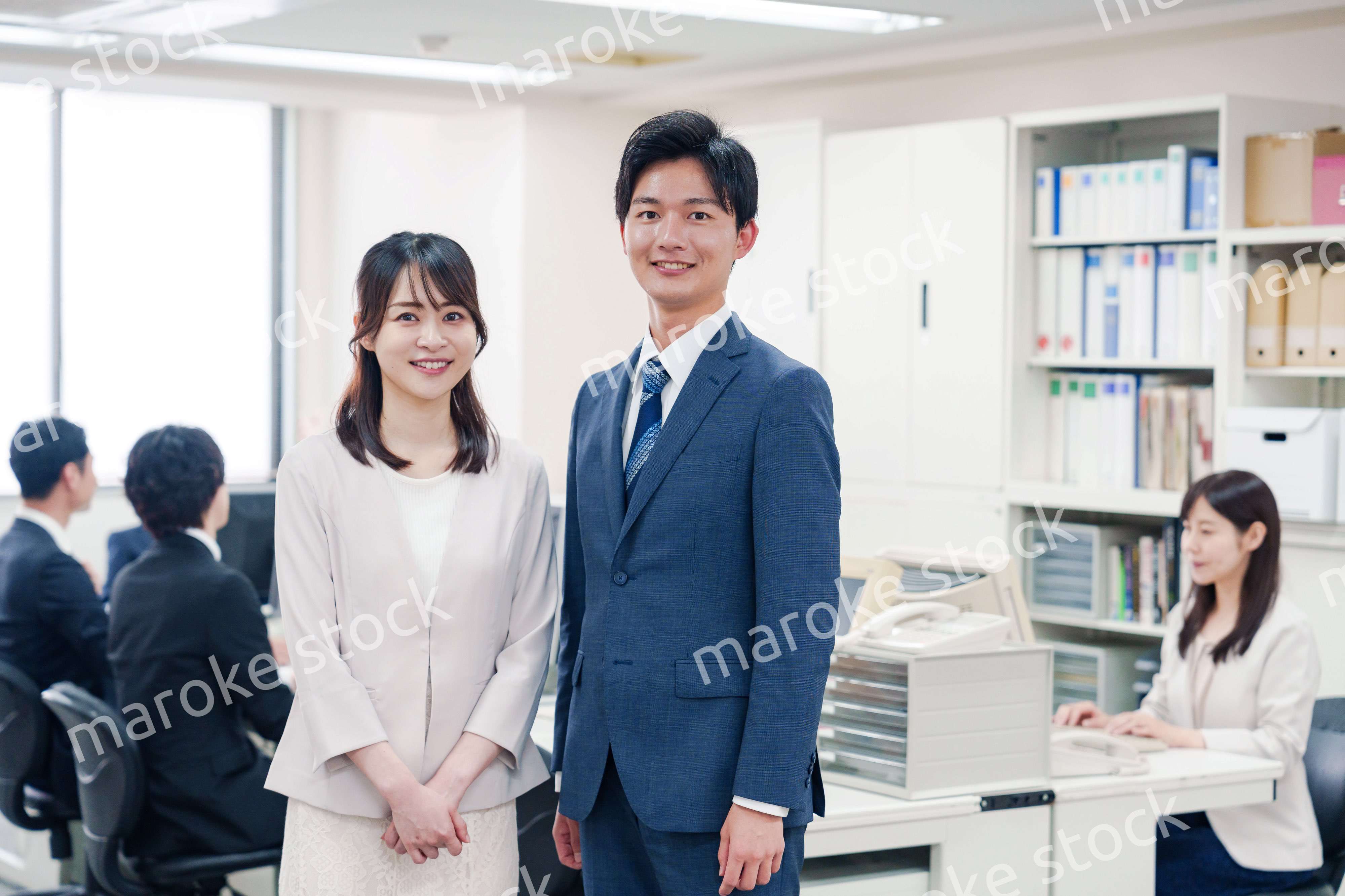 オフィスで笑顔でカメラ目線の男女のビジネスパーソン