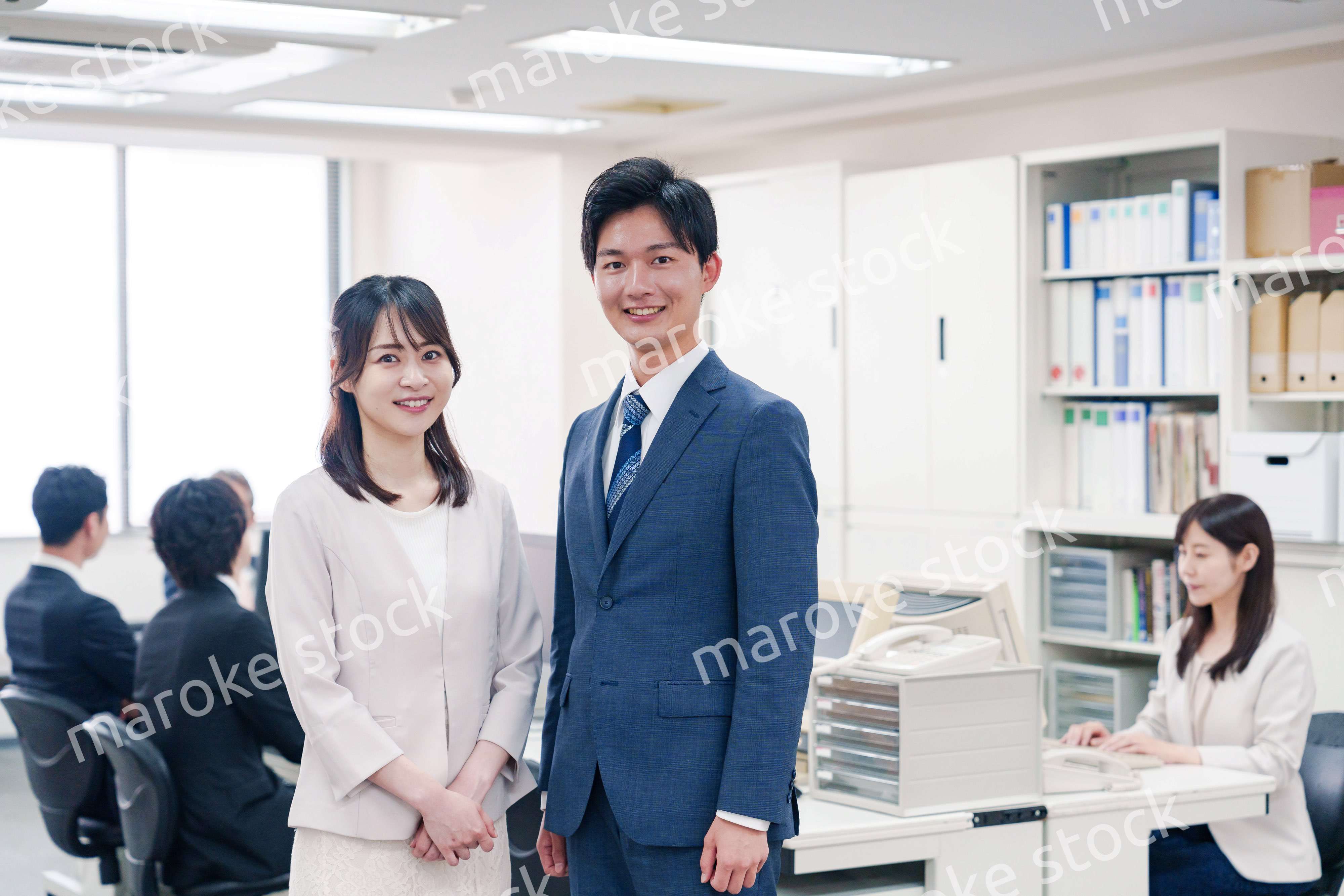 オフィスで笑顔でカメラ目線の男女のビジネスパーソン