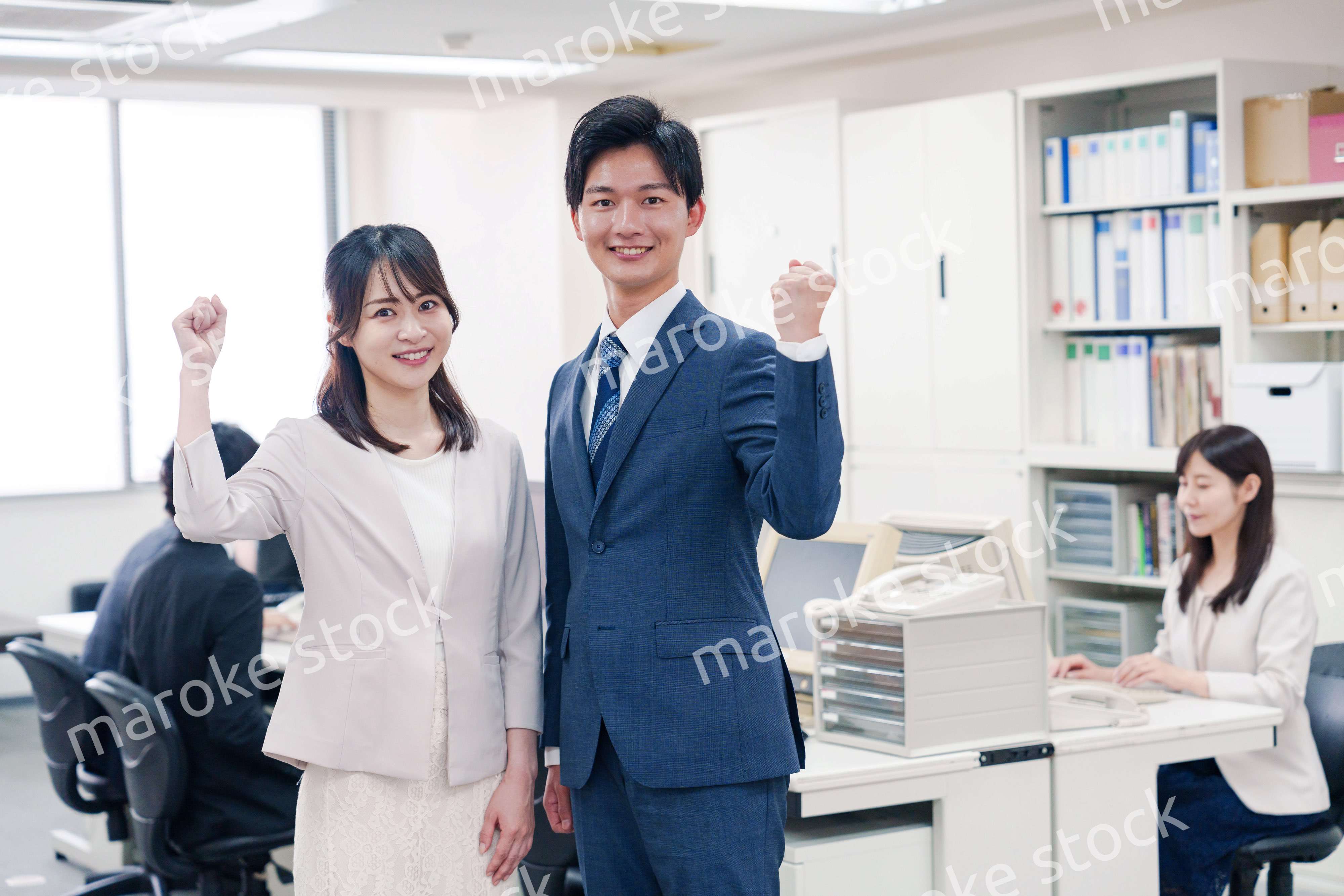 オフィスで笑顔でカメラ目線の男女のビジネスパーソン