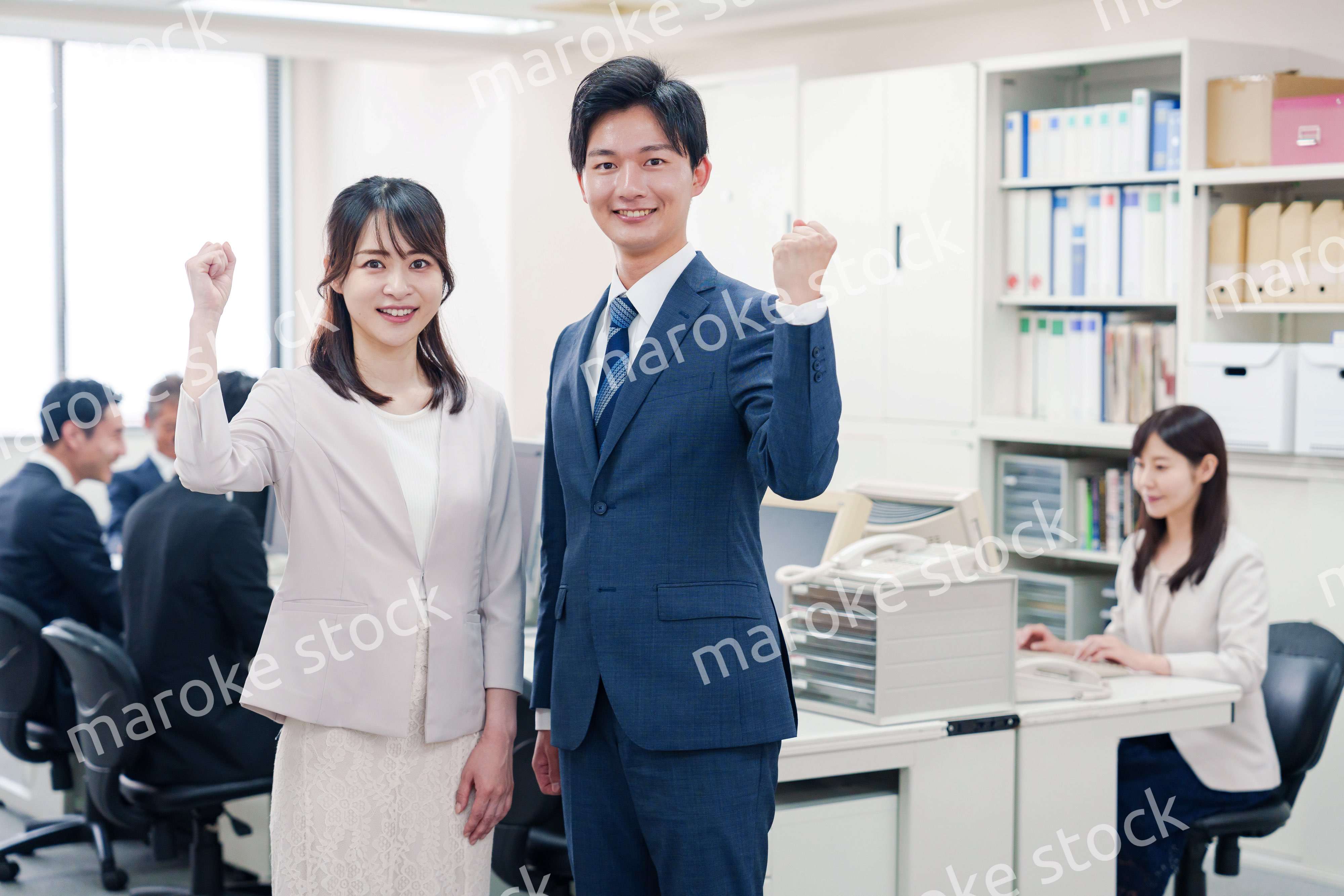 オフィスで笑顔でカメラ目線の男女のビジネスパーソン