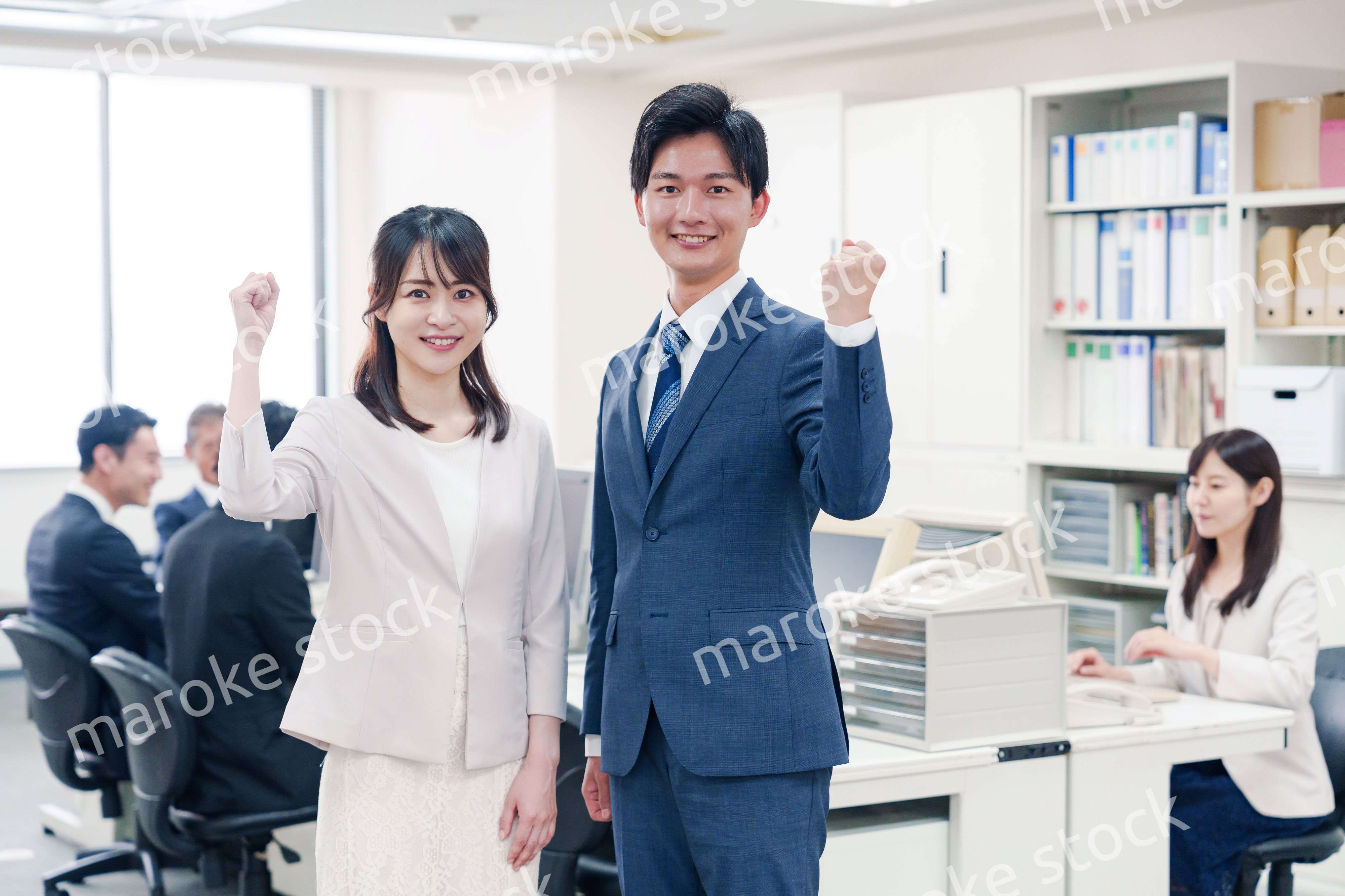 オフィスで笑顔でカメラ目線の男女のビジネスパーソン