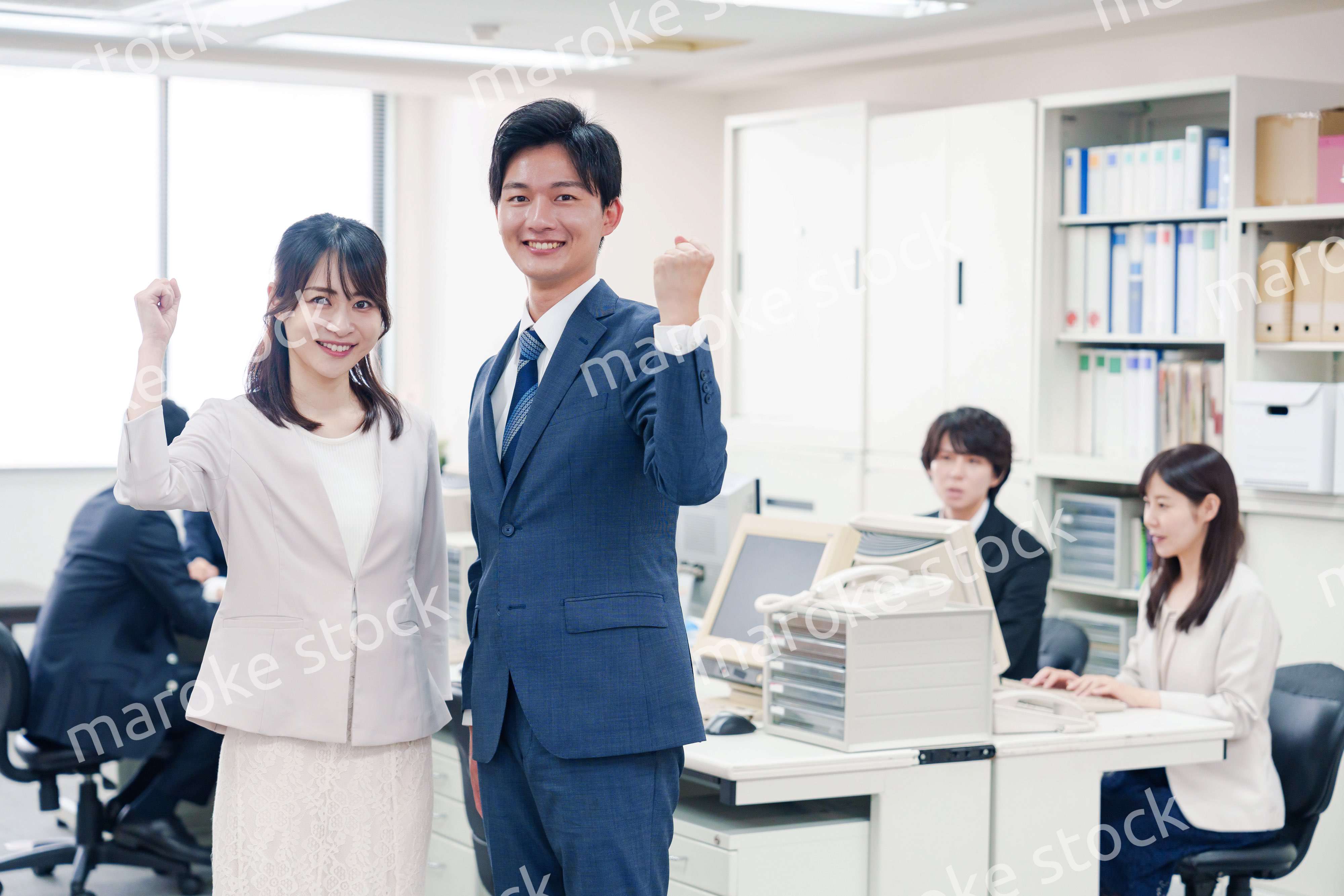 オフィスで笑顔でカメラ目線の男女のビジネスパーソン