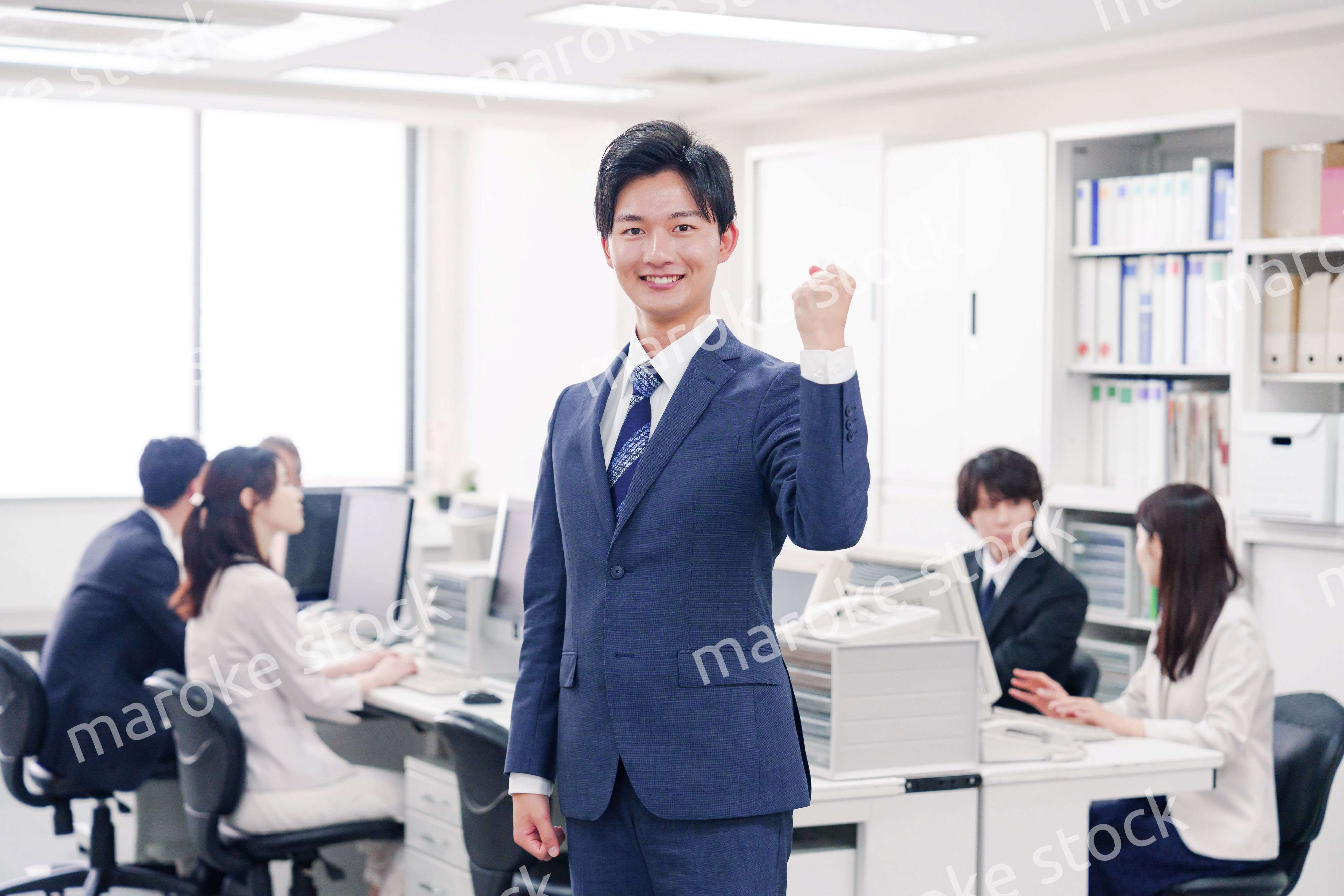 オフィスでガッツポーズをするスーツを着たビジネスマン