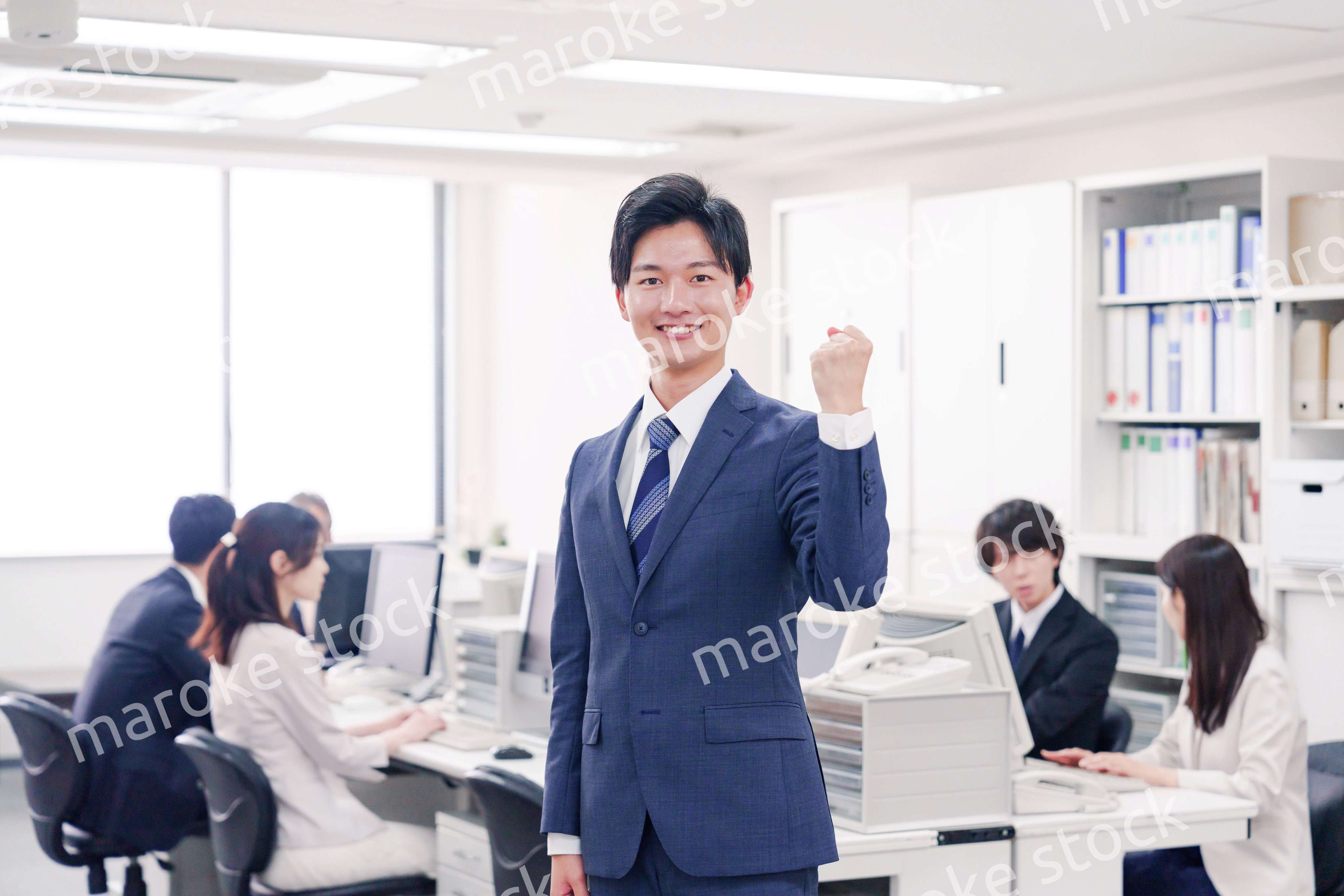 オフィスでガッツポーズをするスーツを着たビジネスマン