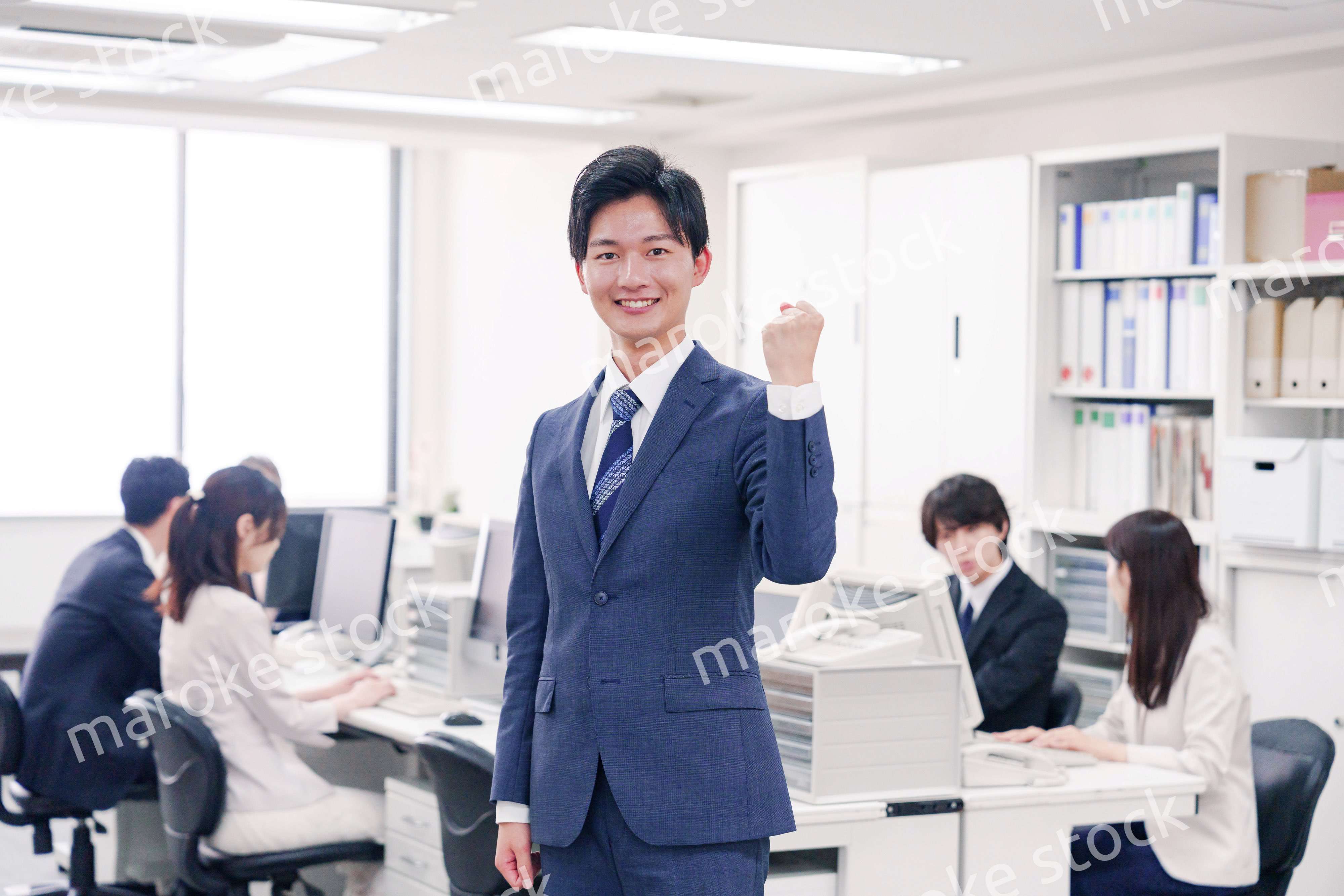 オフィスでガッツポーズをするスーツを着たビジネスマン