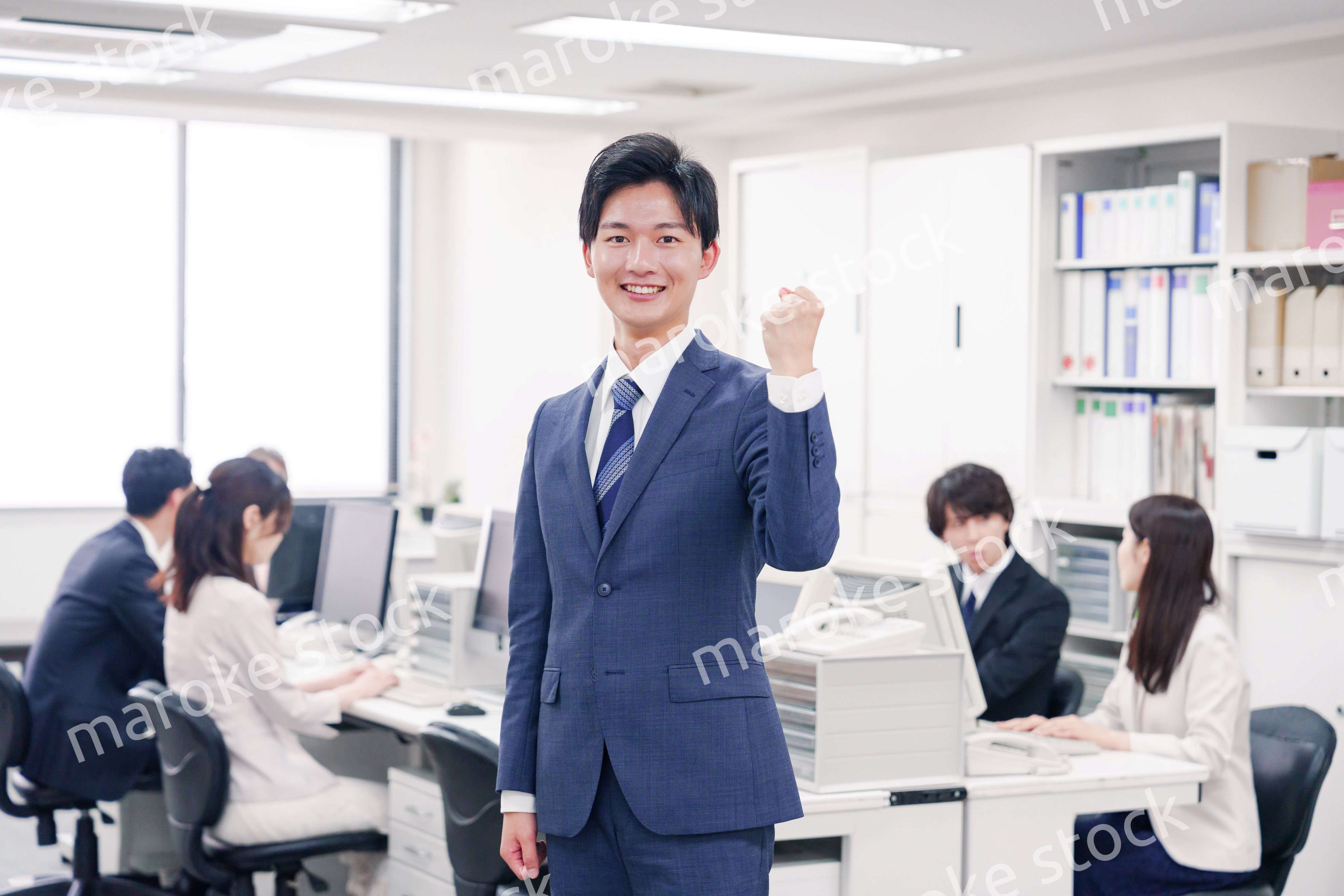 オフィスでガッツポーズをするスーツを着たビジネスマン