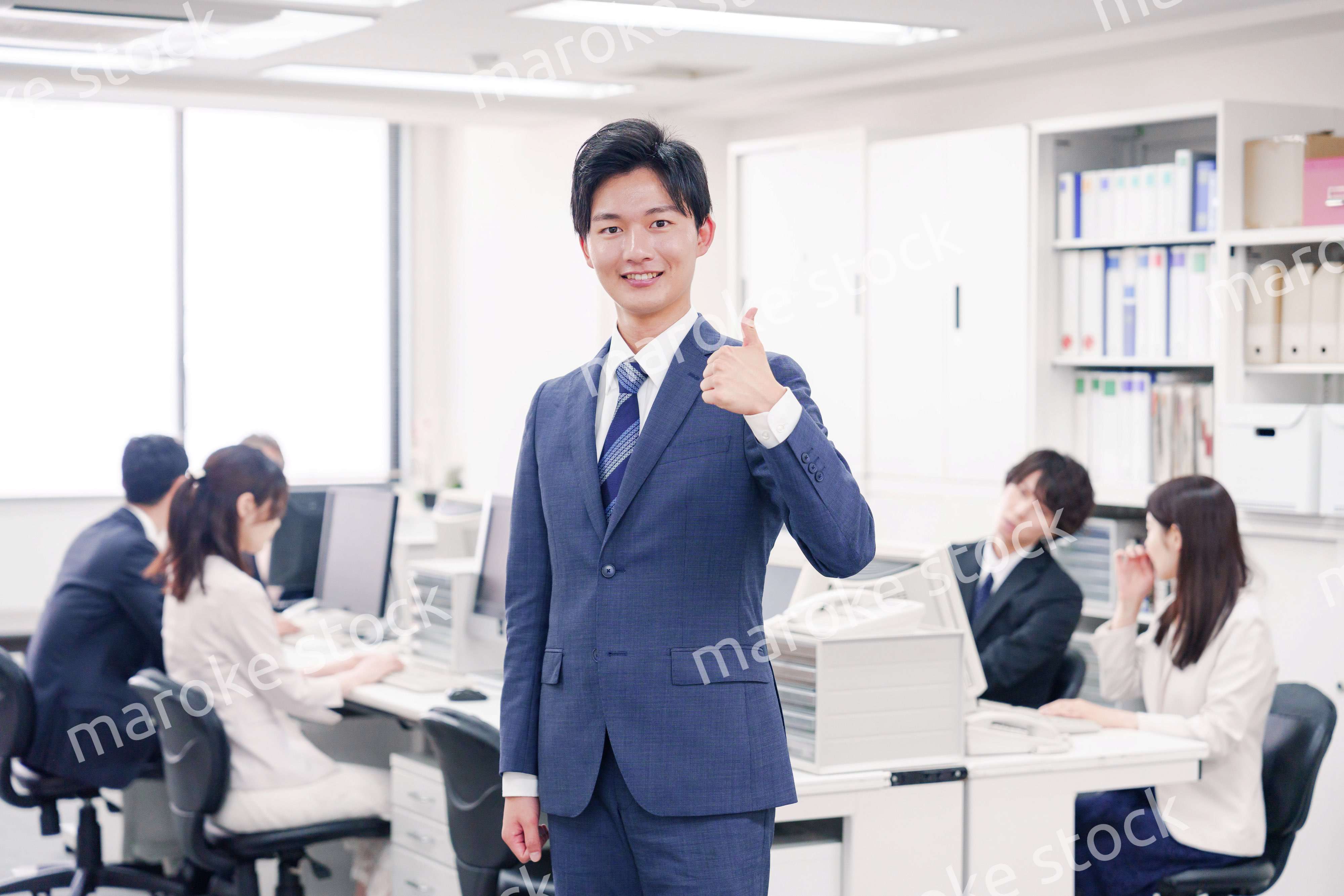 オフィスでグッドサインをするスーツを着たビジネスマン