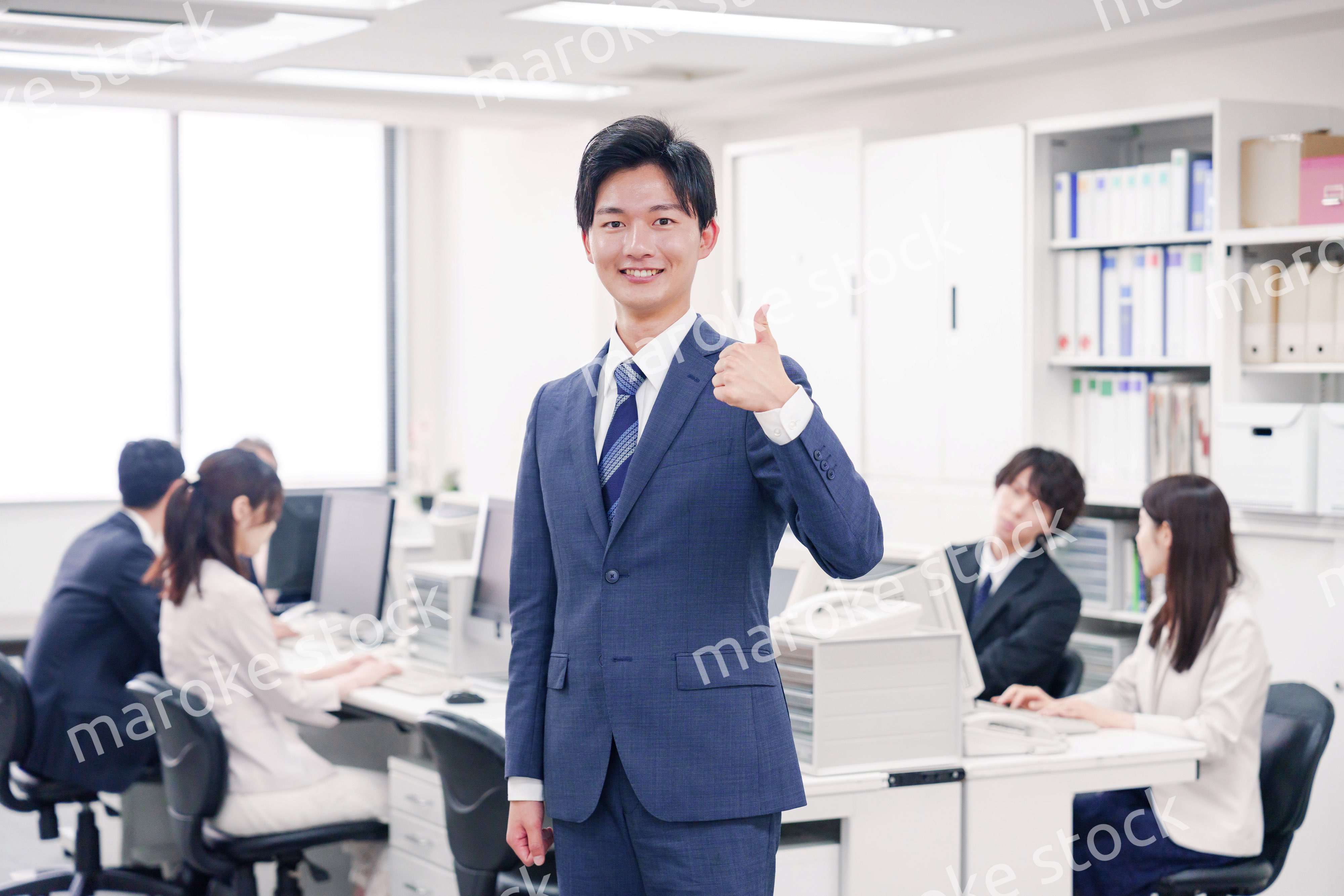 オフィスでグッドサインをするスーツを着たビジネスマン
