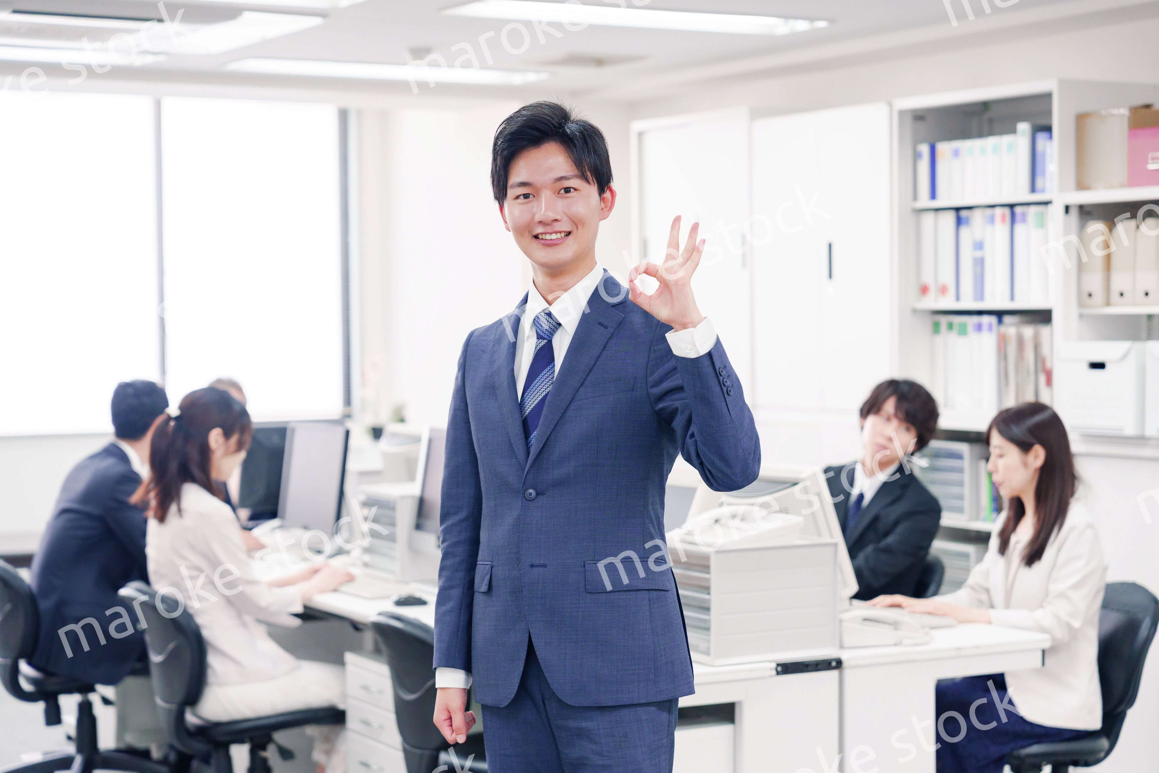 オフィスでグッドサインをするスーツを着たビジネスマン