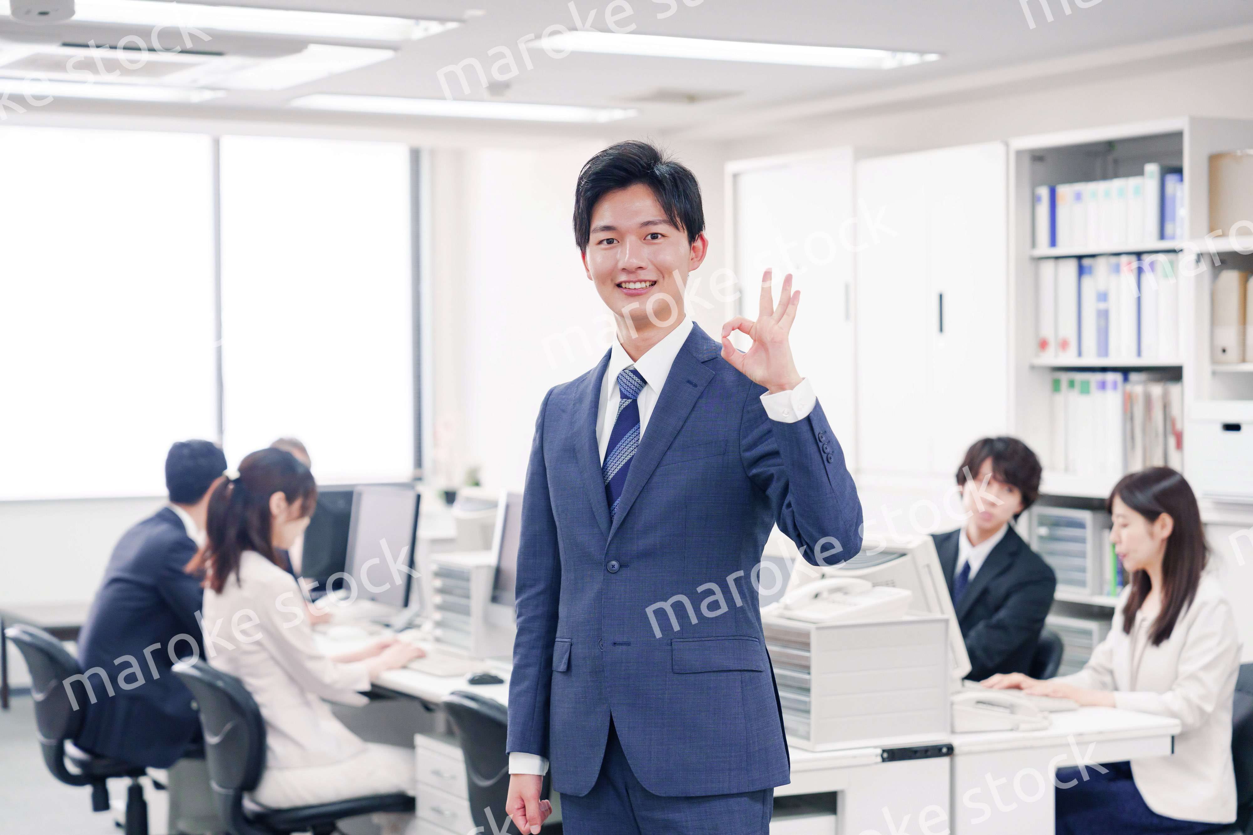 オフィスでグッドサインをするスーツを着たビジネスマン