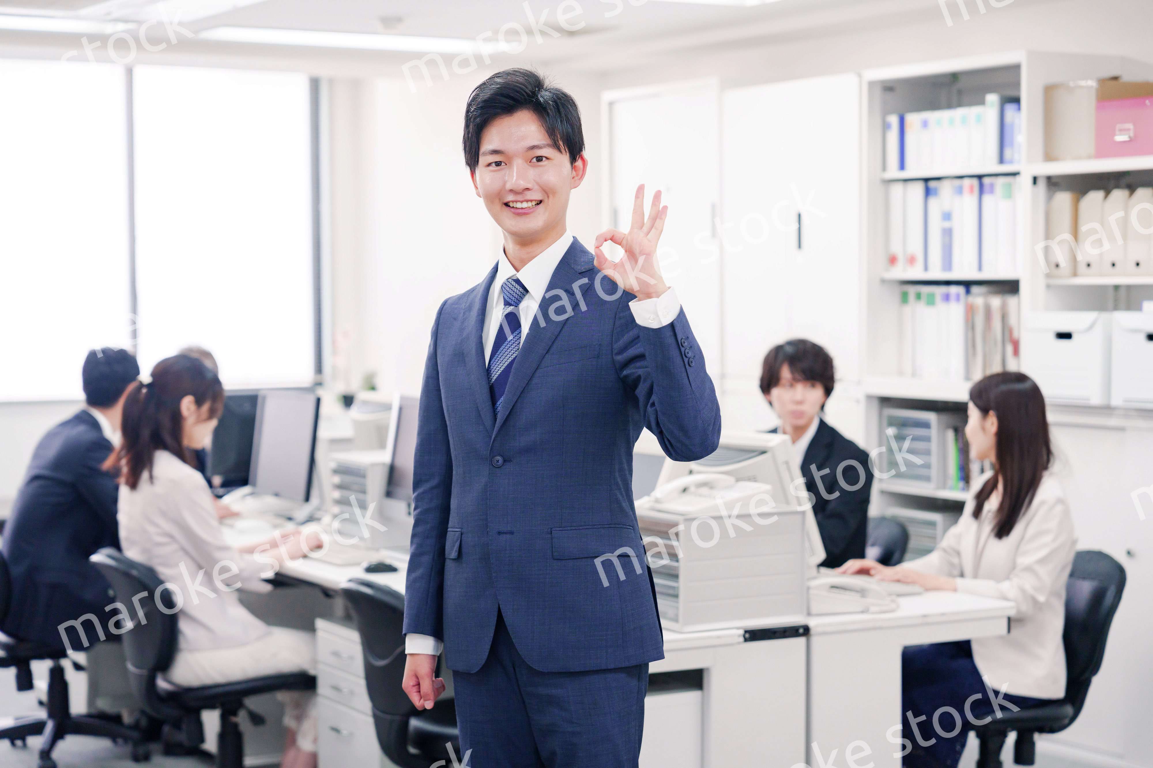 オフィスでグッドサインをするスーツを着たビジネスマン