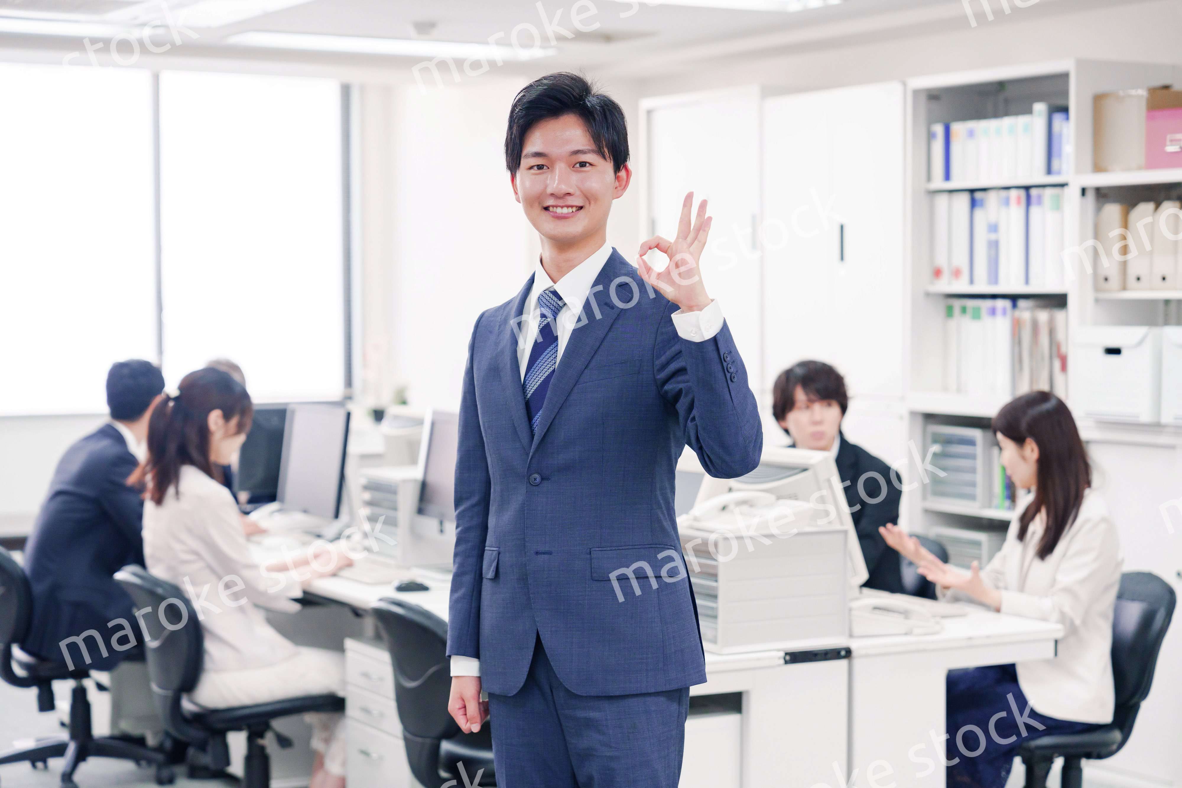 オフィスでグッドサインをするスーツを着たビジネスマン
