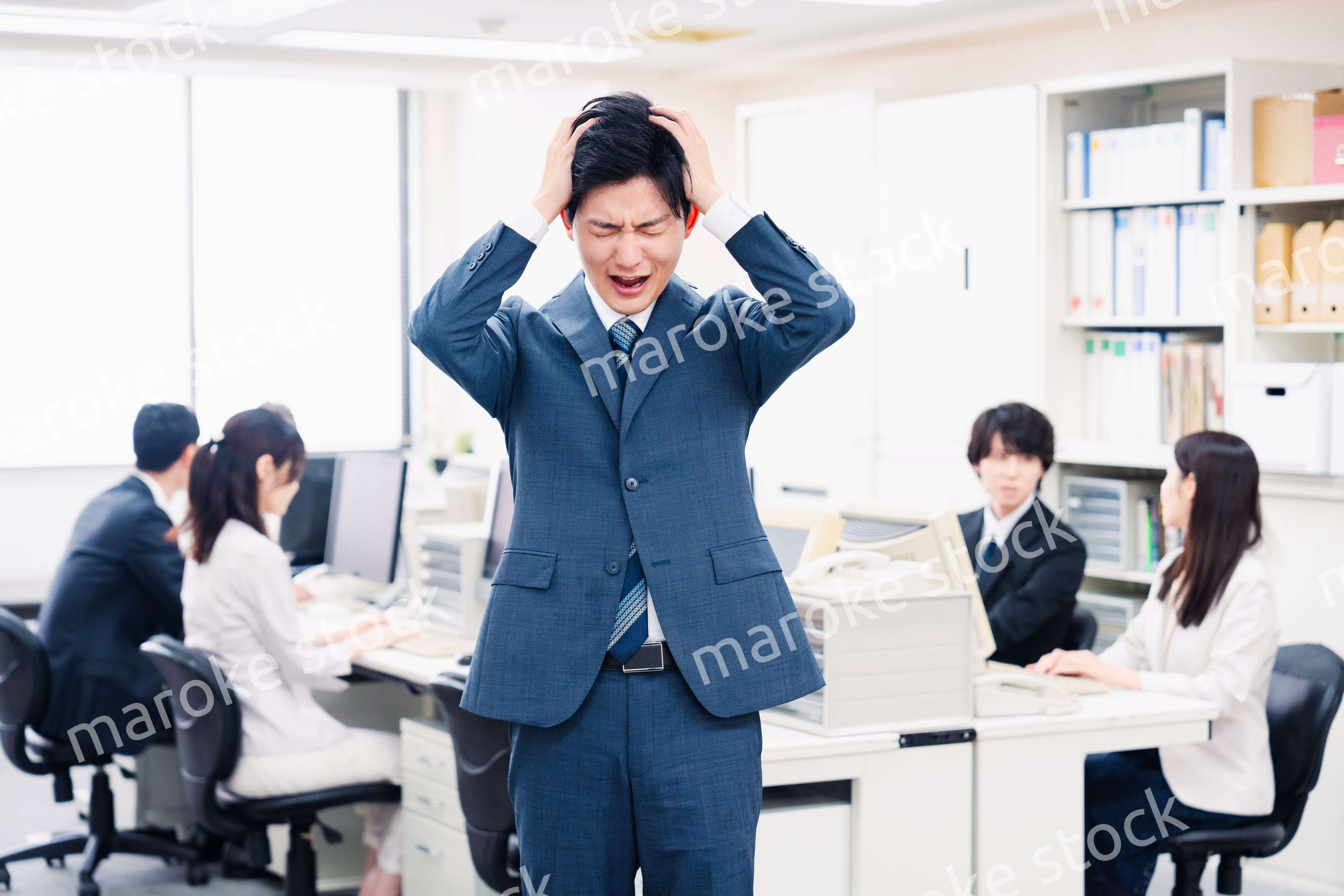 オフィスで頭を抱える若いビジネスマン