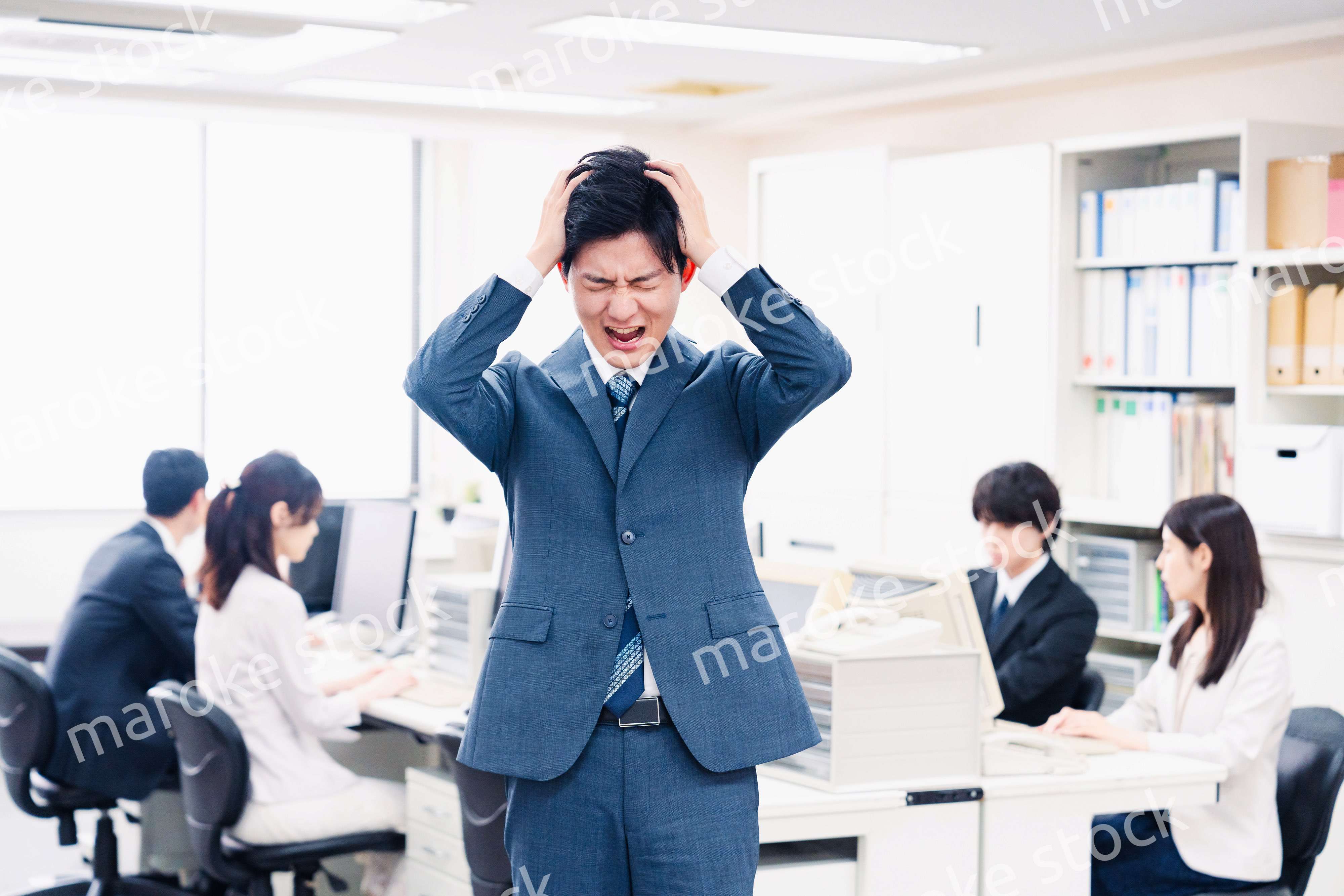 オフィスで頭を抱える若いビジネスマン