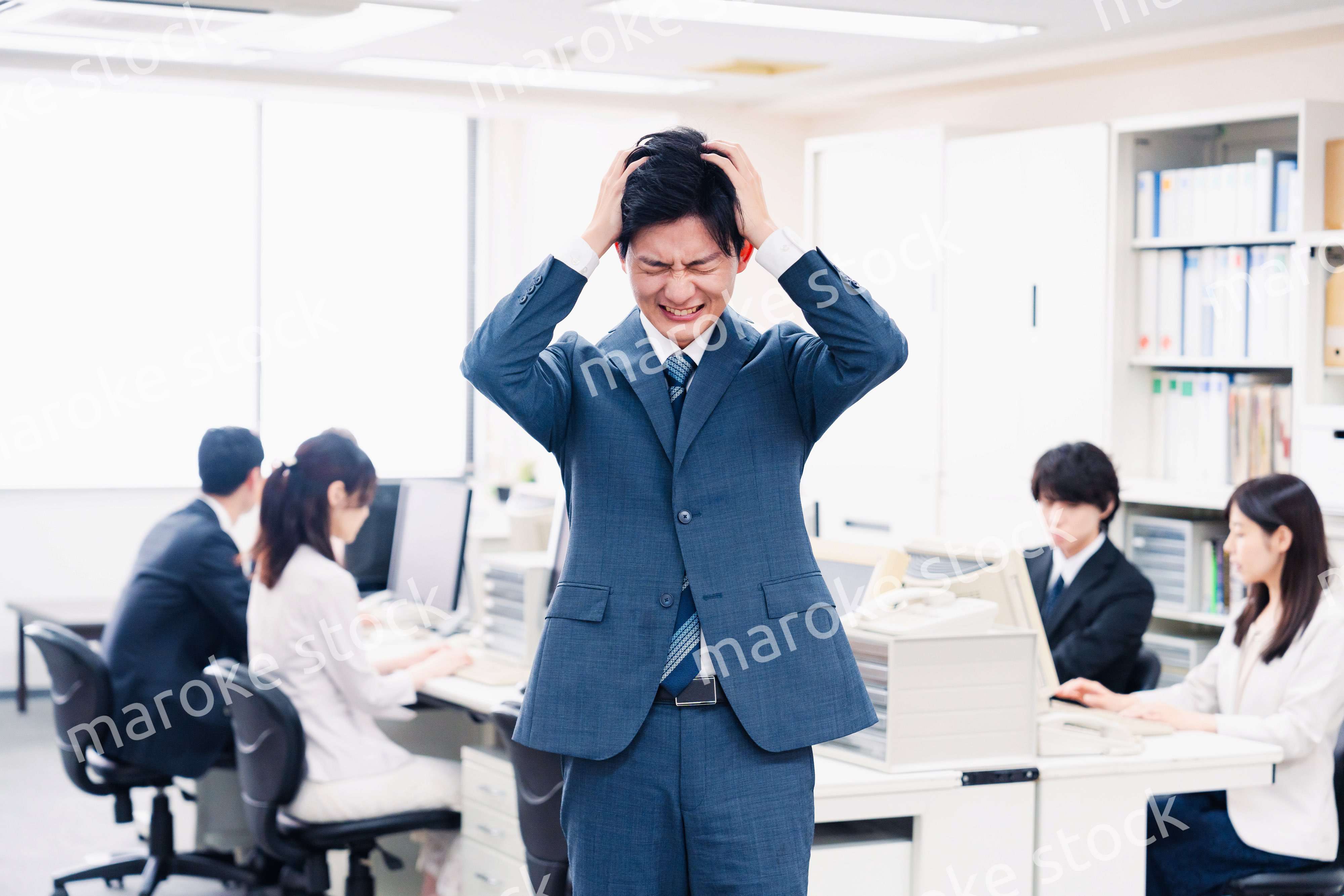 オフィスで頭を抱える若いビジネスマン